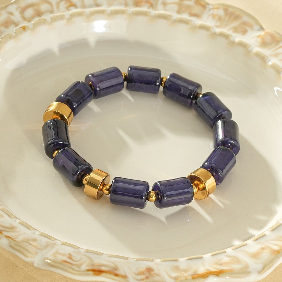 Bracciale elastico cilindrico in resina blu ambra con anelli distanziatori dorati