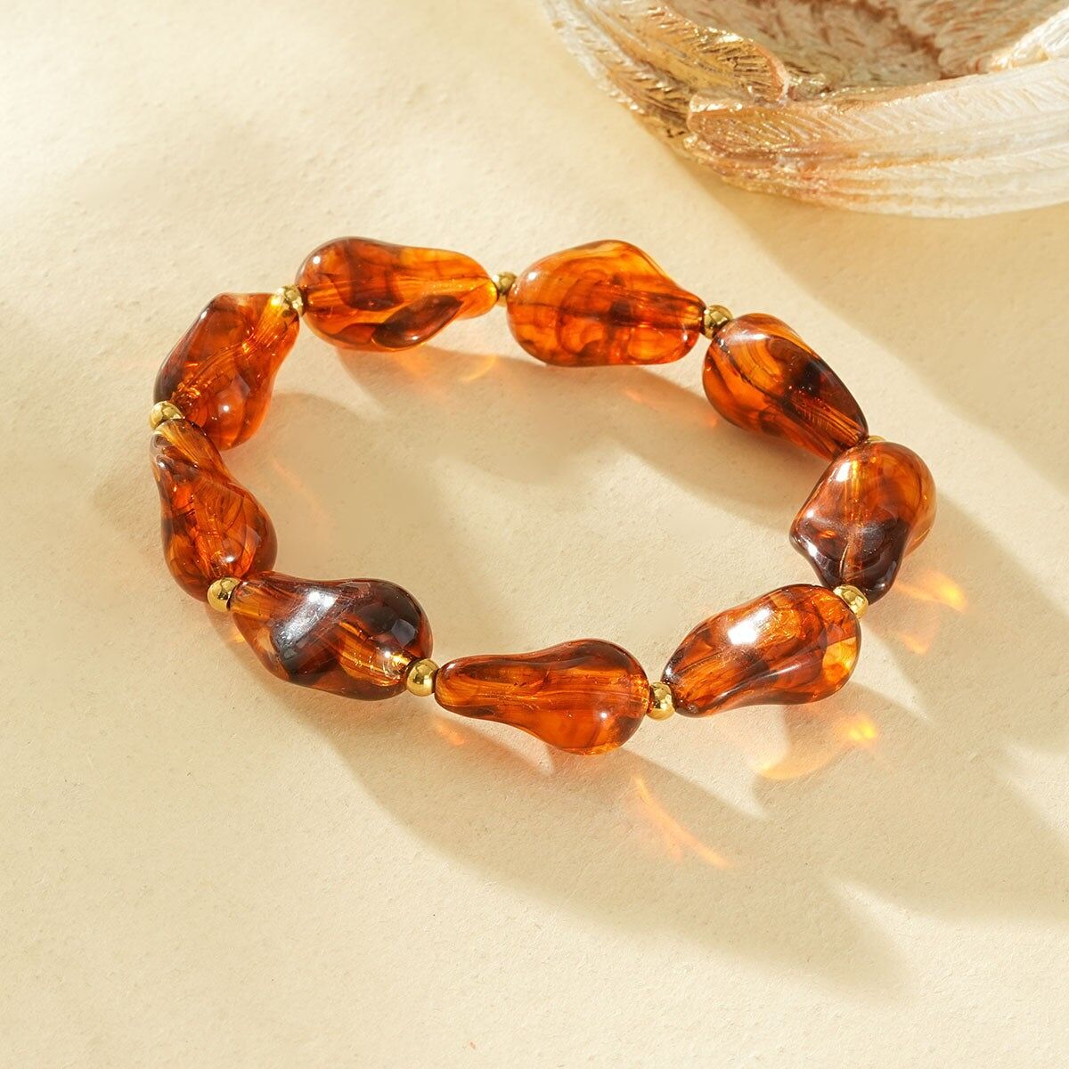 Bracciale elastico in resina con forme irregolari, color ambra marrone, separatori in oro