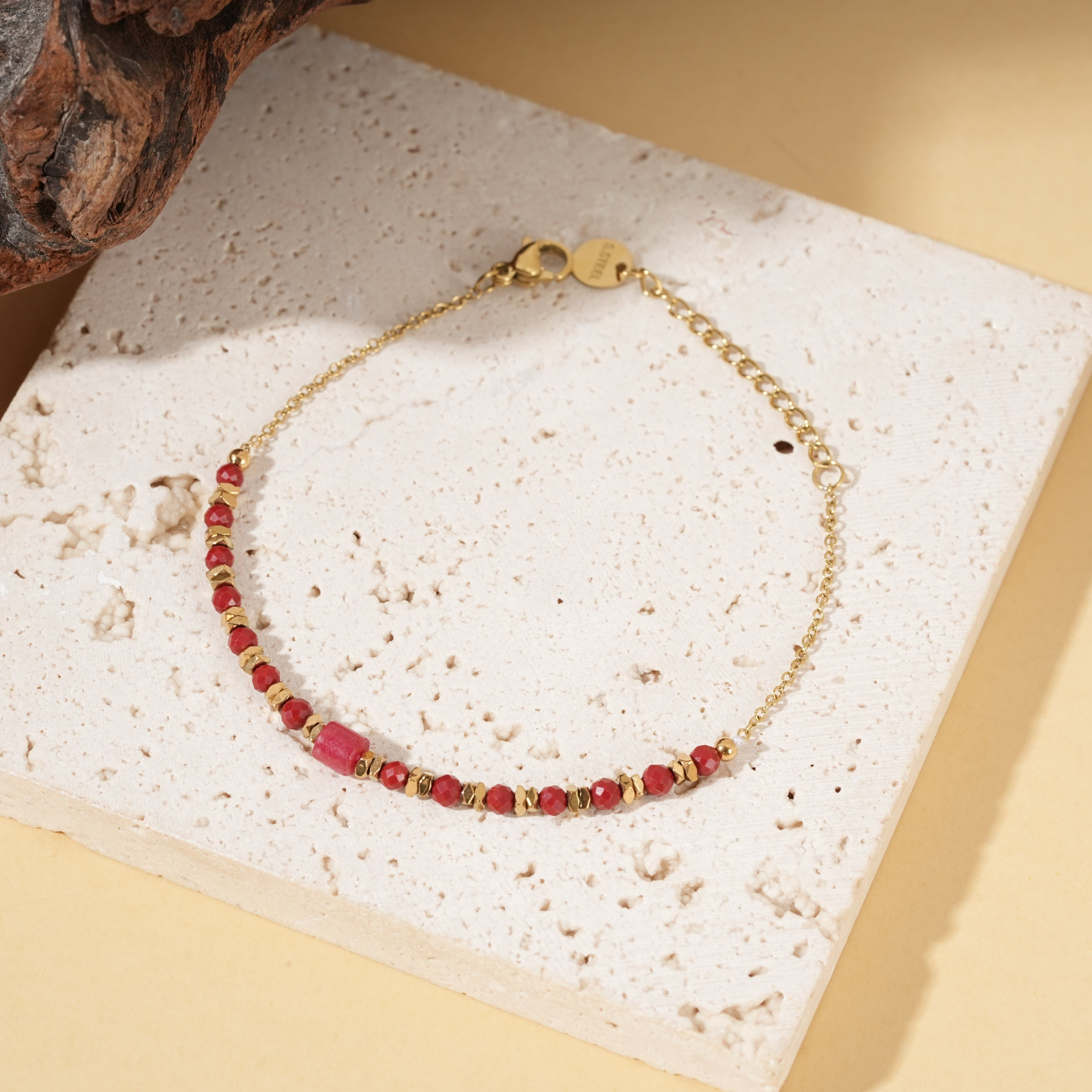 Bracciale in oro con catena sottile e pietre rosse, pietra centrale cilindrica.