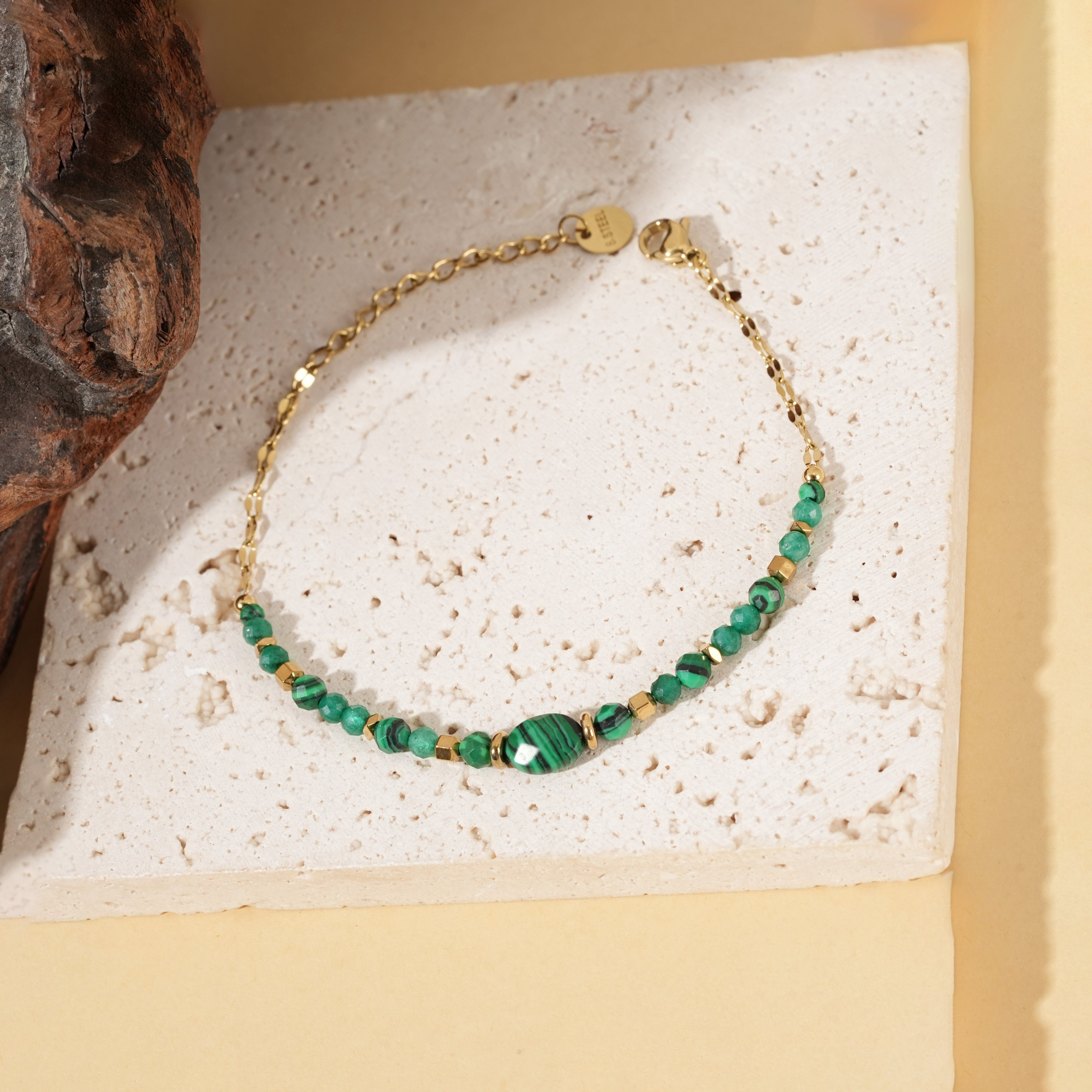 Bracciale in oro con catena sottile e pietre di malachite sintetica, caratterizzato da una pietra centrale ovale.