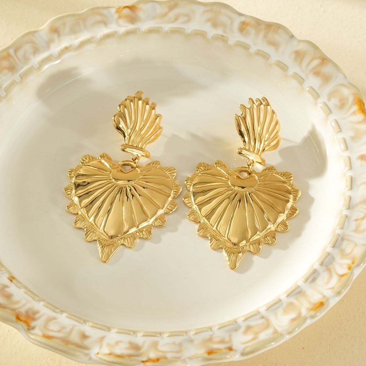 Orecchini pendenti color oro con un grande cuore bombato e strutturato