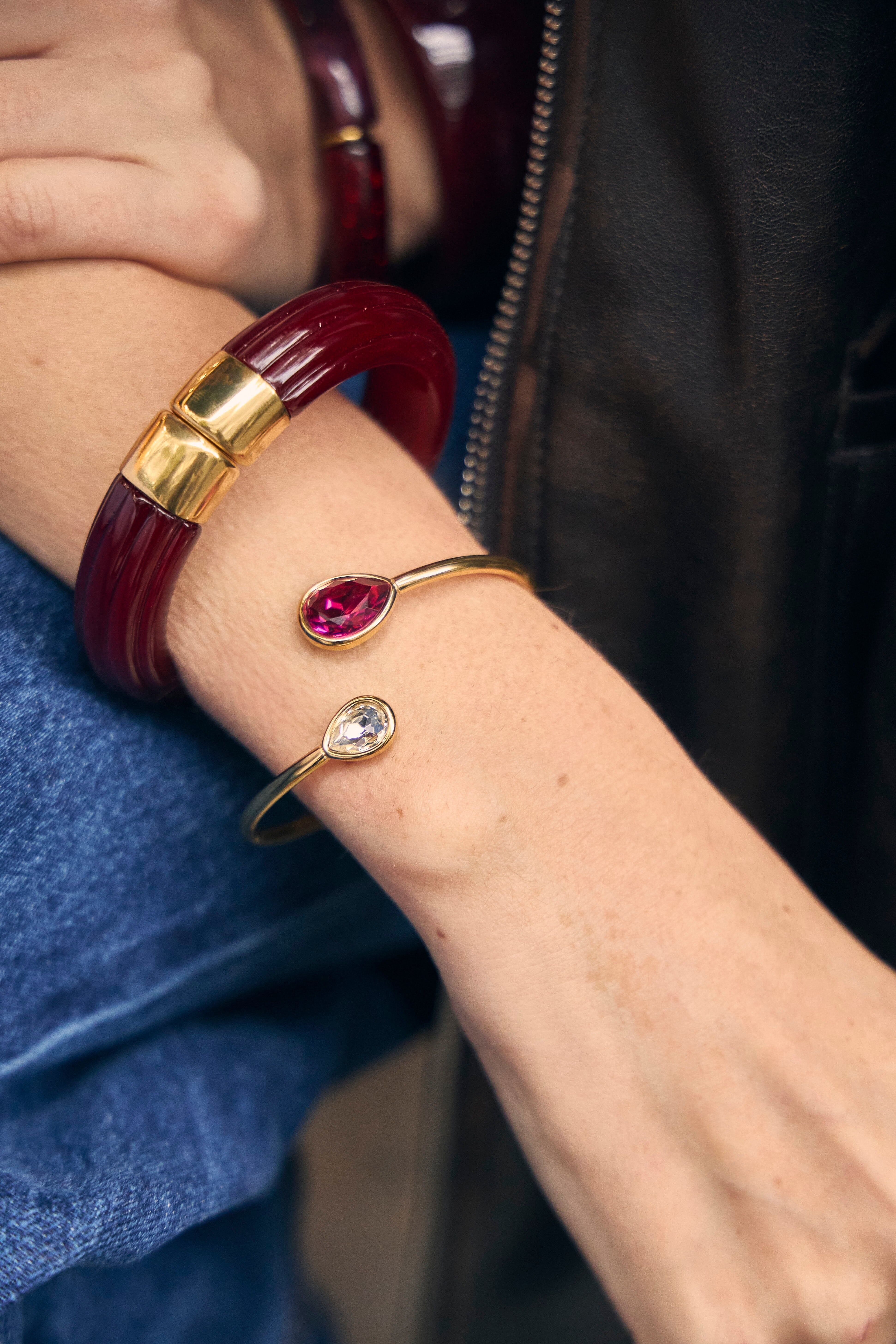 Bracciale rigido staccabile color oro, aperto sul davanti, con cristalli di vetro a forma di lacrima bianchi e fucsia