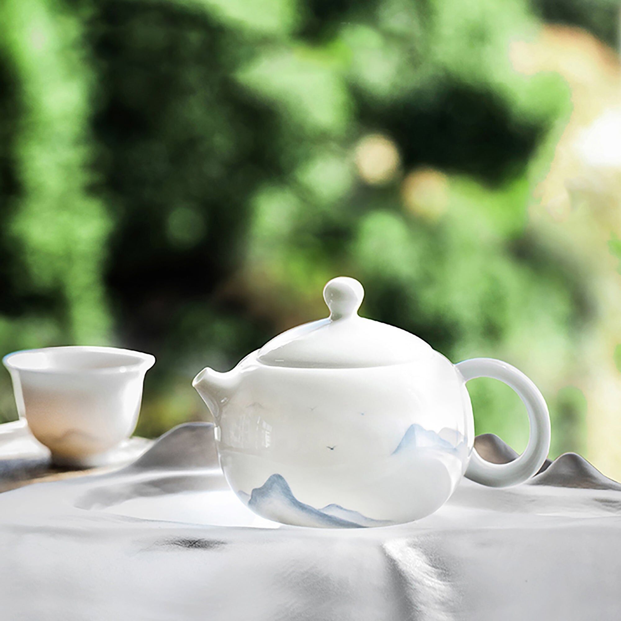 Teekanne aus weißem Porzellan mit Bergmotiv