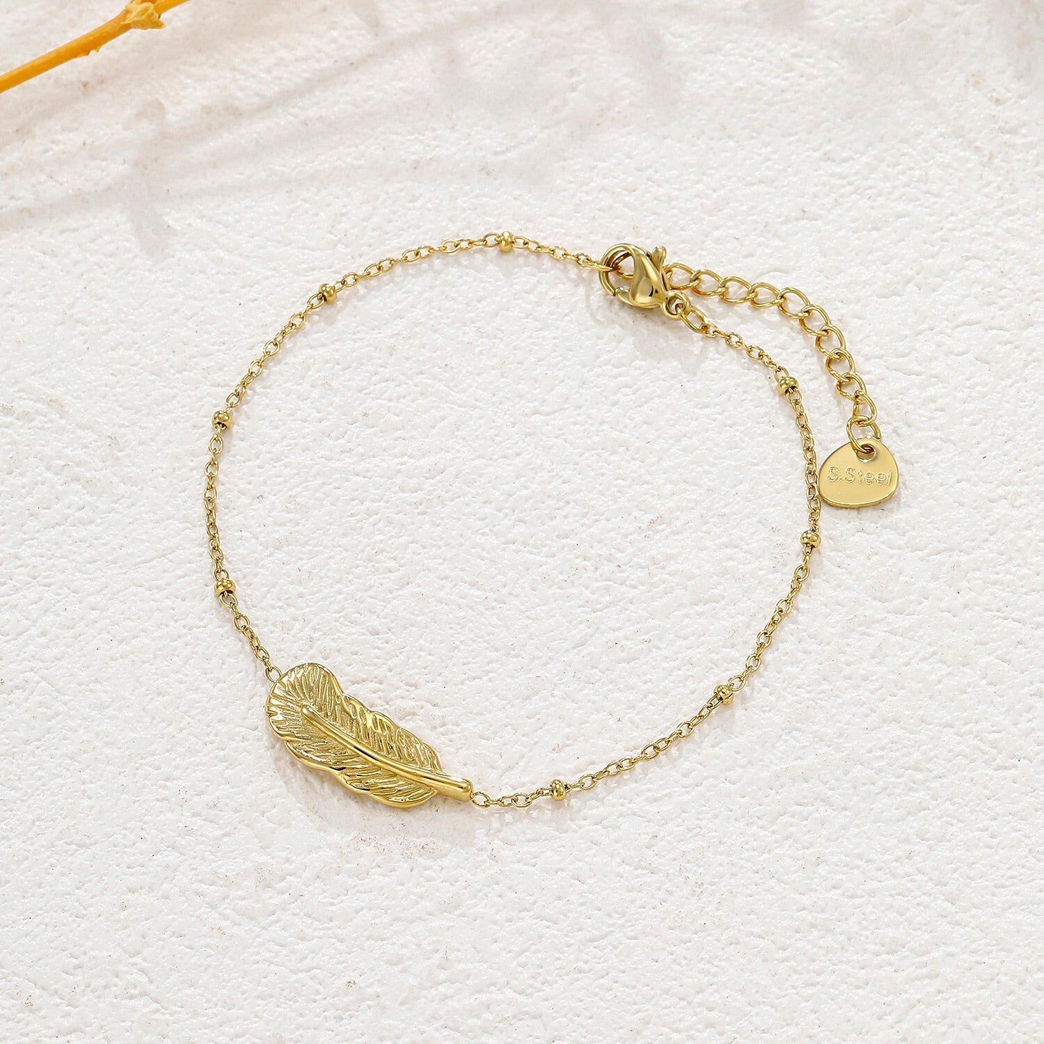 Bracciale in oro con catena sottile e pendente a forma di piuma testurizzata