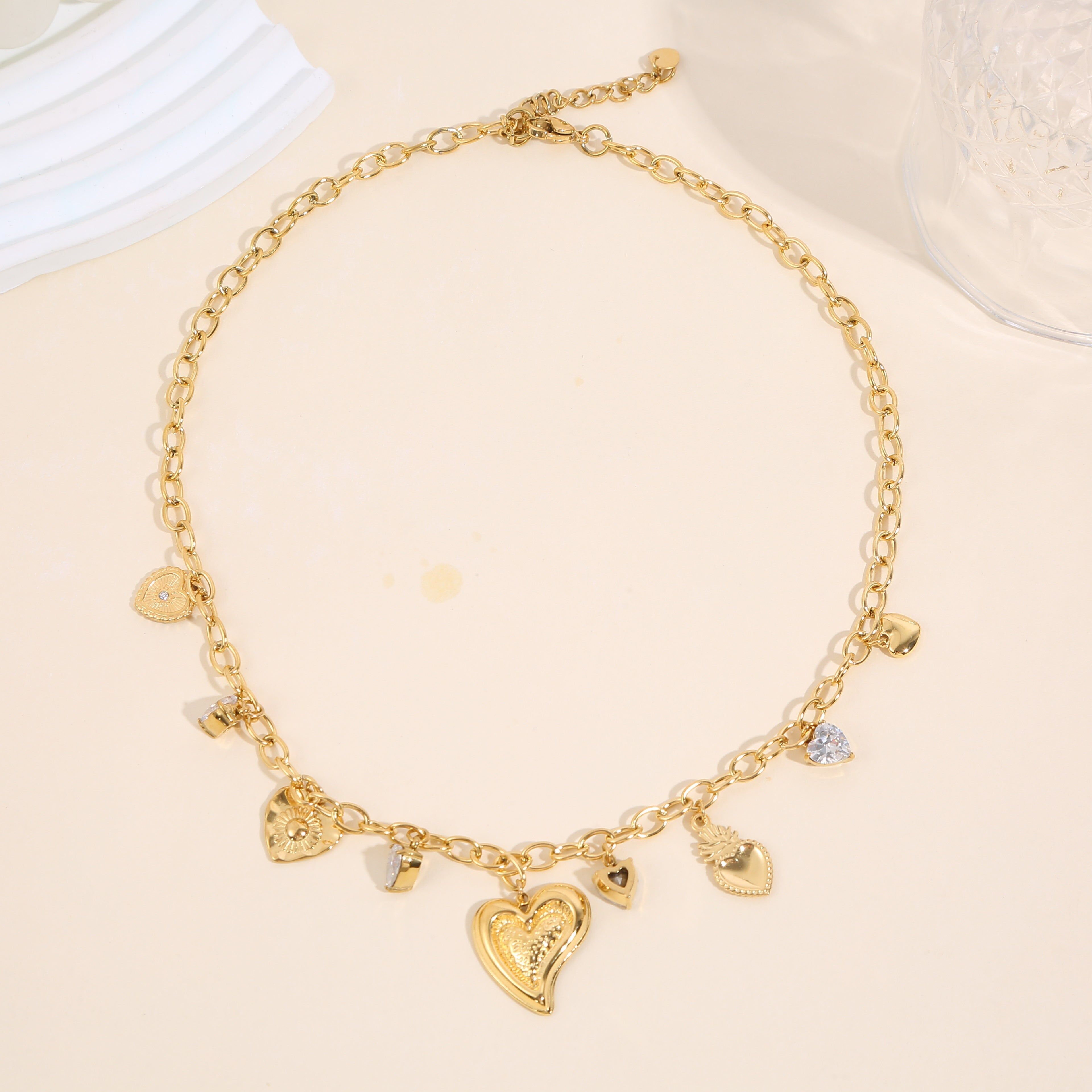 Collana in oro con vari pendenti: cuori lisci bombati, strass, ex voto