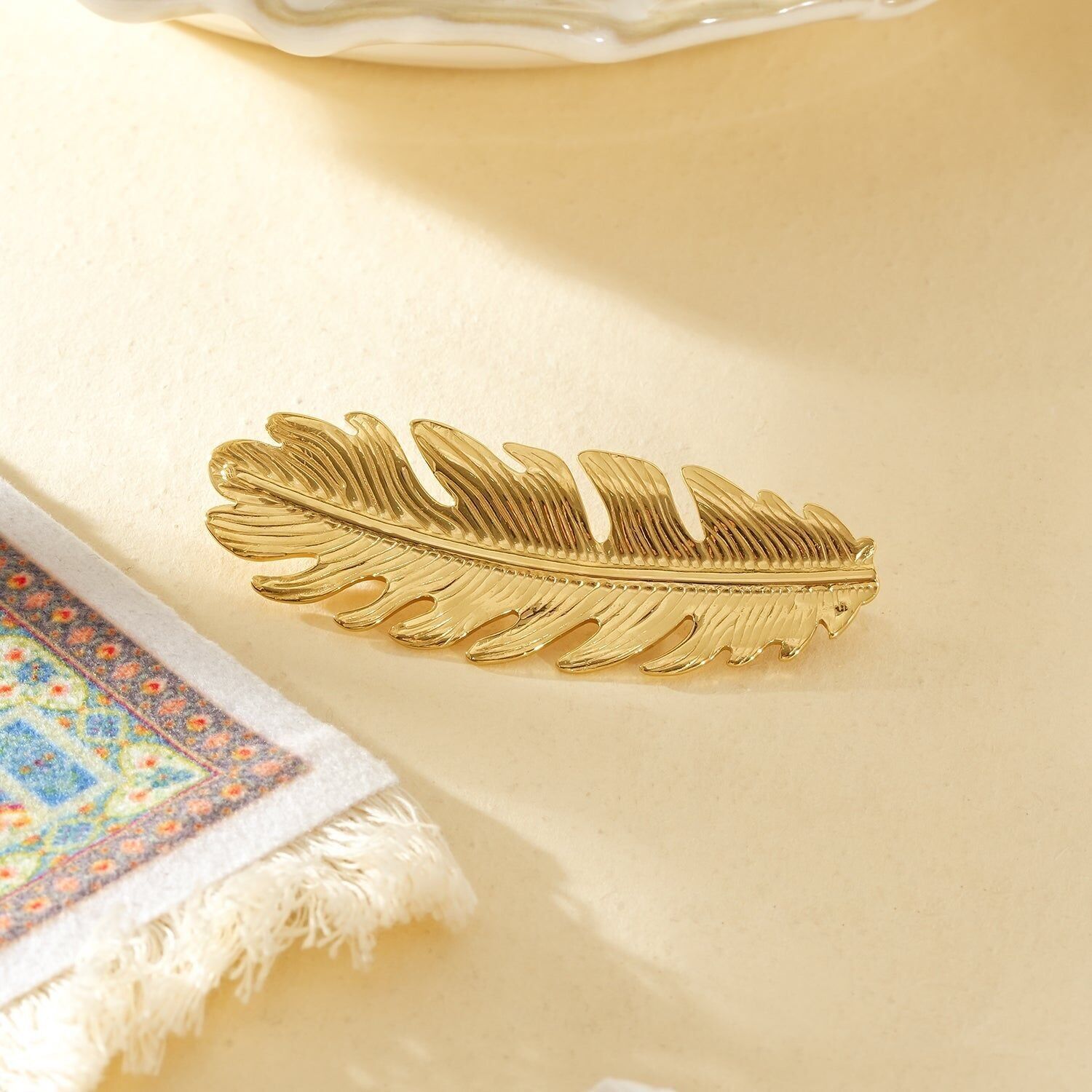 Spilla in oro con piuma testurizzata