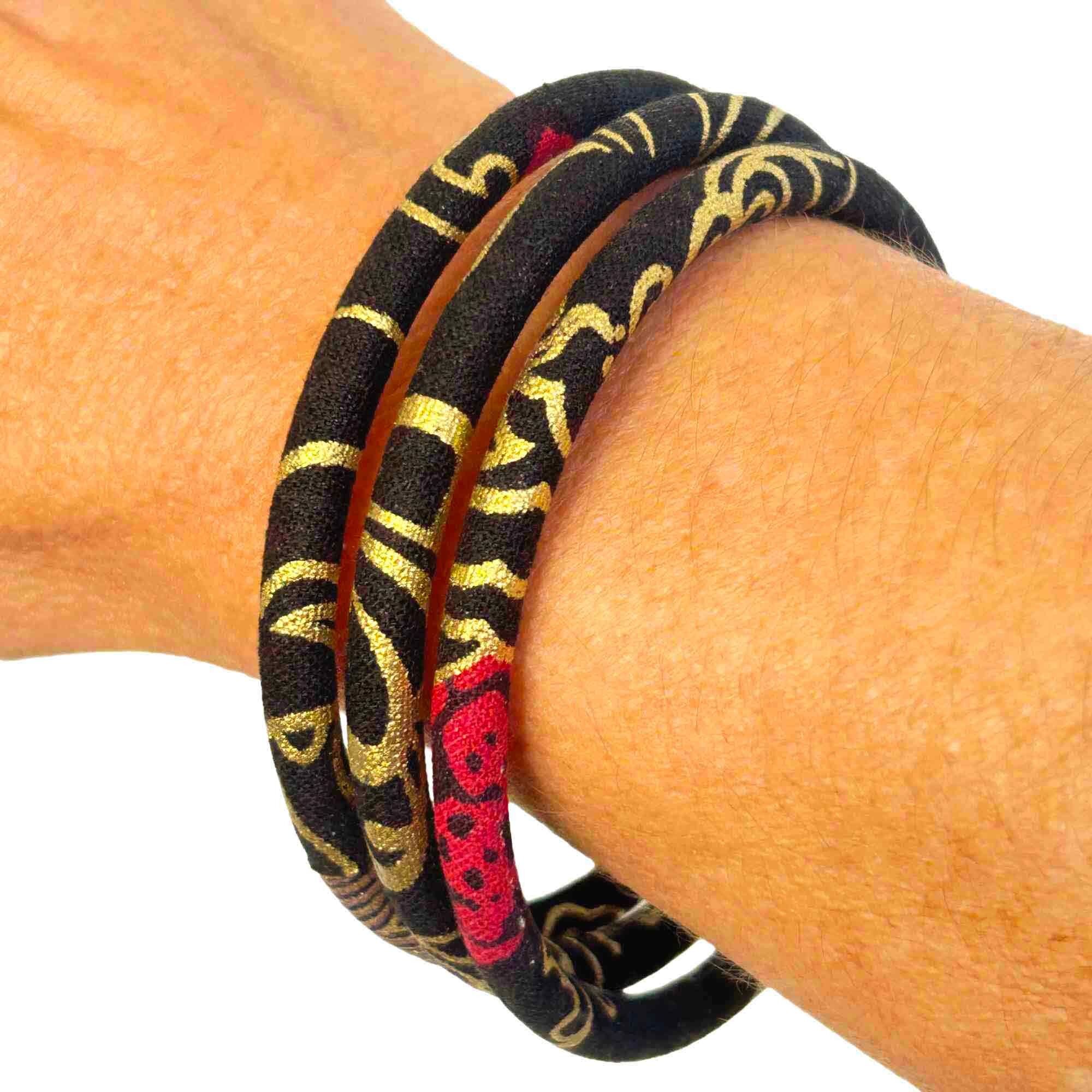 Brazalete japonés con carpas koi doradas sobre fondo negro.