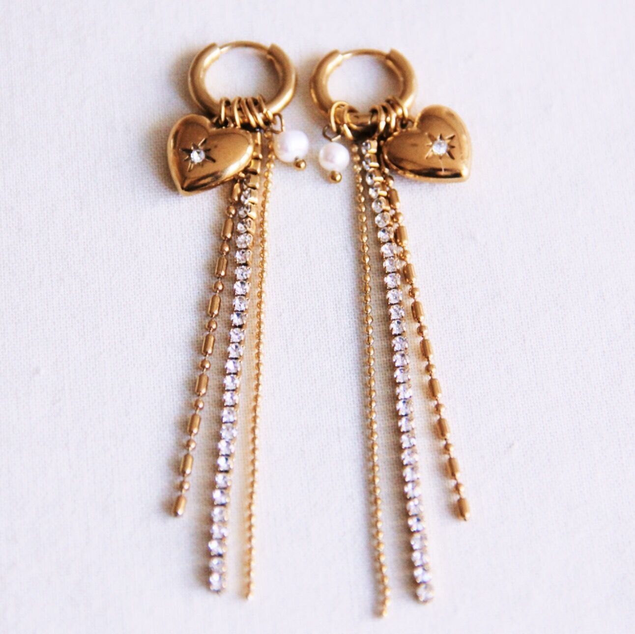 Boucle d'oreille ornée de fils brillants, de strass, d'un cœur et d'une perle