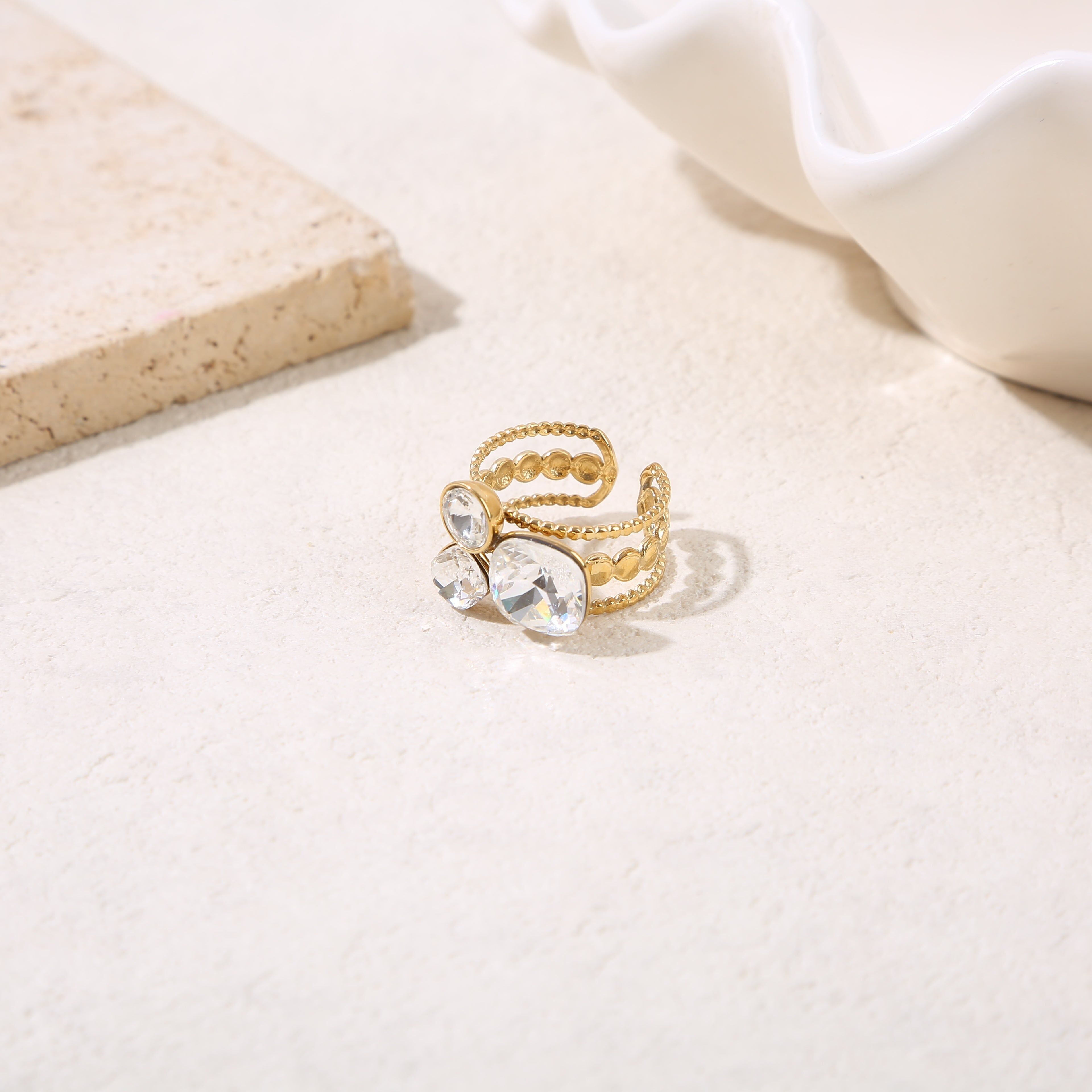 Anello regolabile placcato oro con tre rami e tre strass di varie forme.