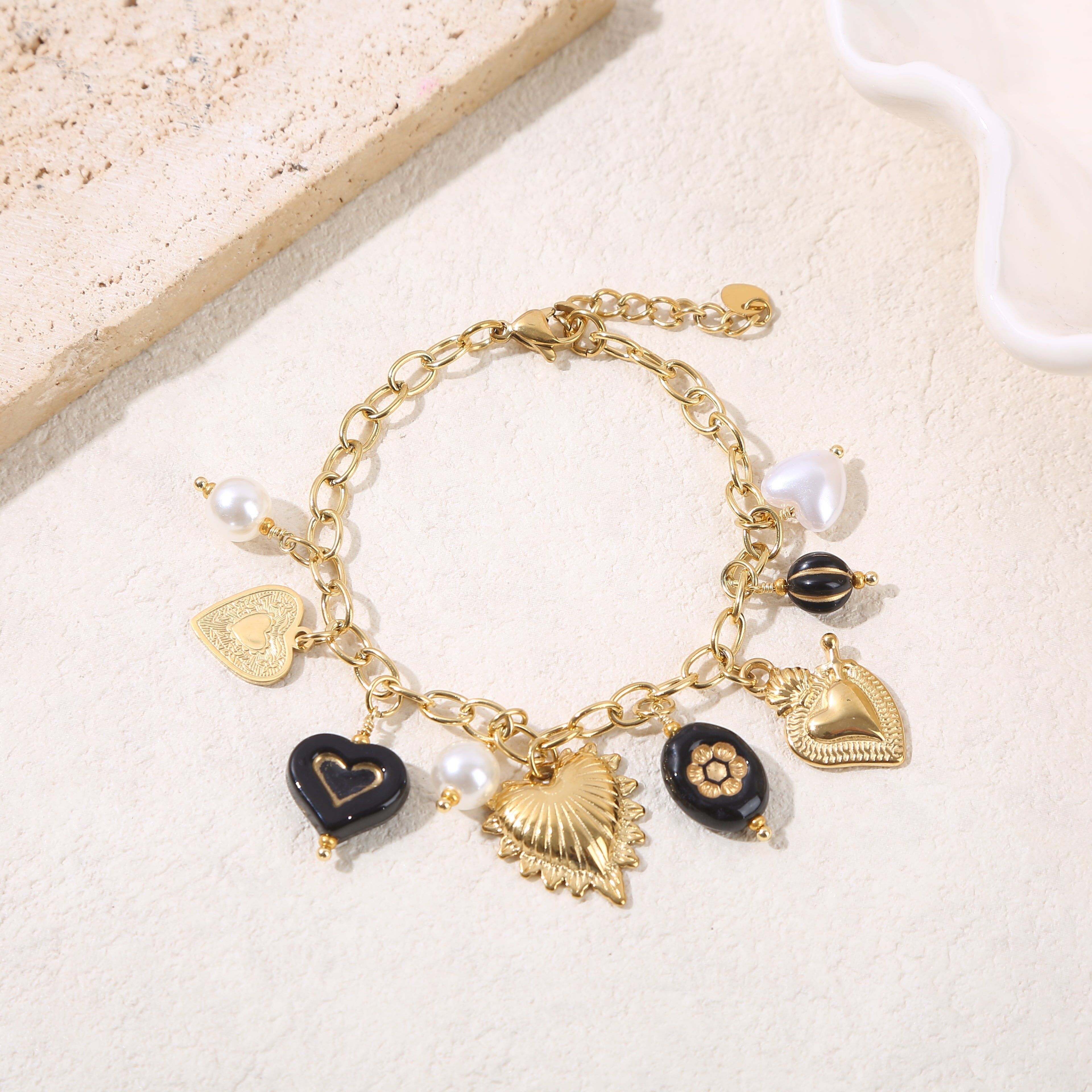 Bracciale a catena in oro con ciondoli a forma di cuore e resina nera