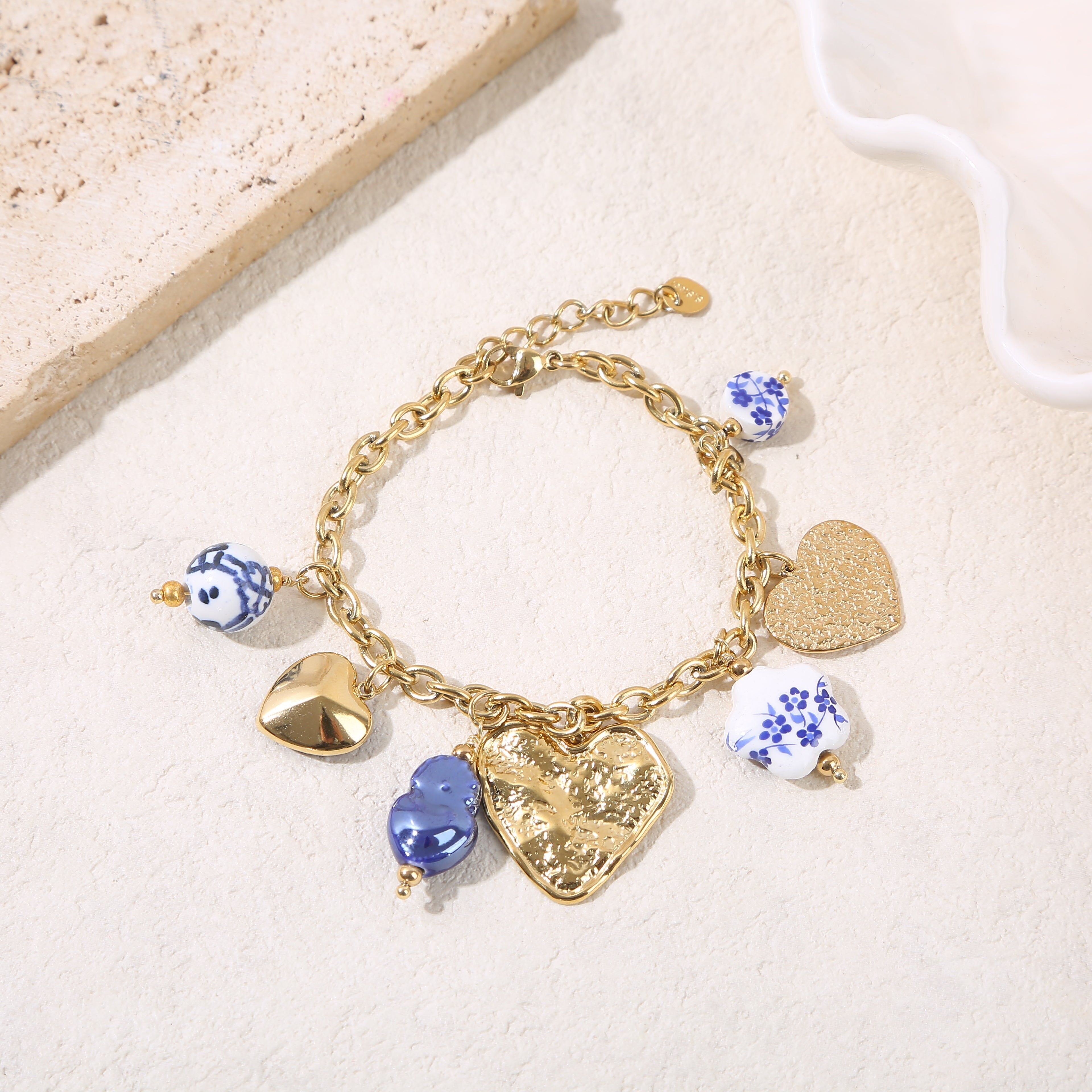 Bracciale a catena in oro con pendenti blu e una grande placca a forma di cuore martellato