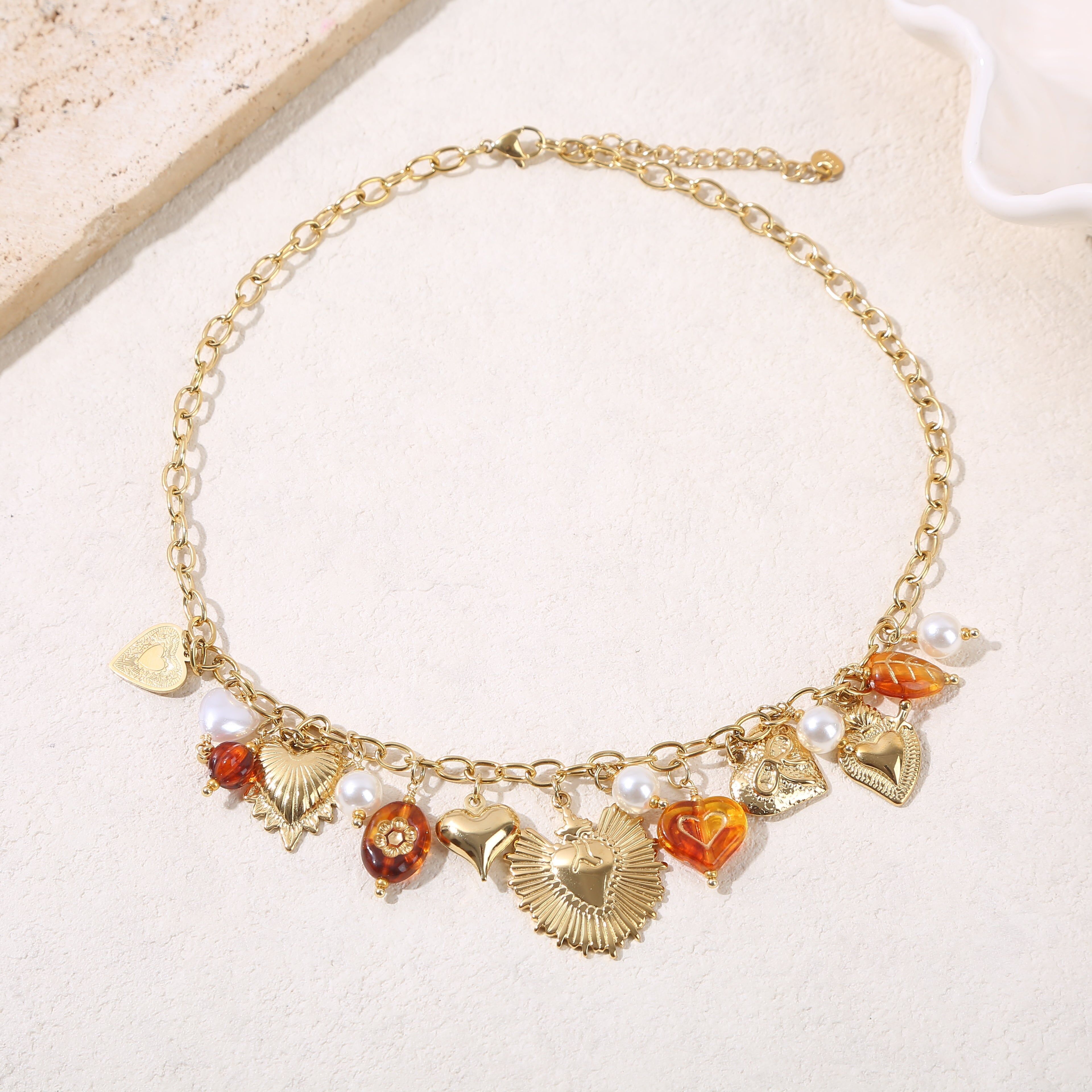 Collana con catena in oro con ciondoli a forma di cuore e resina ambrata