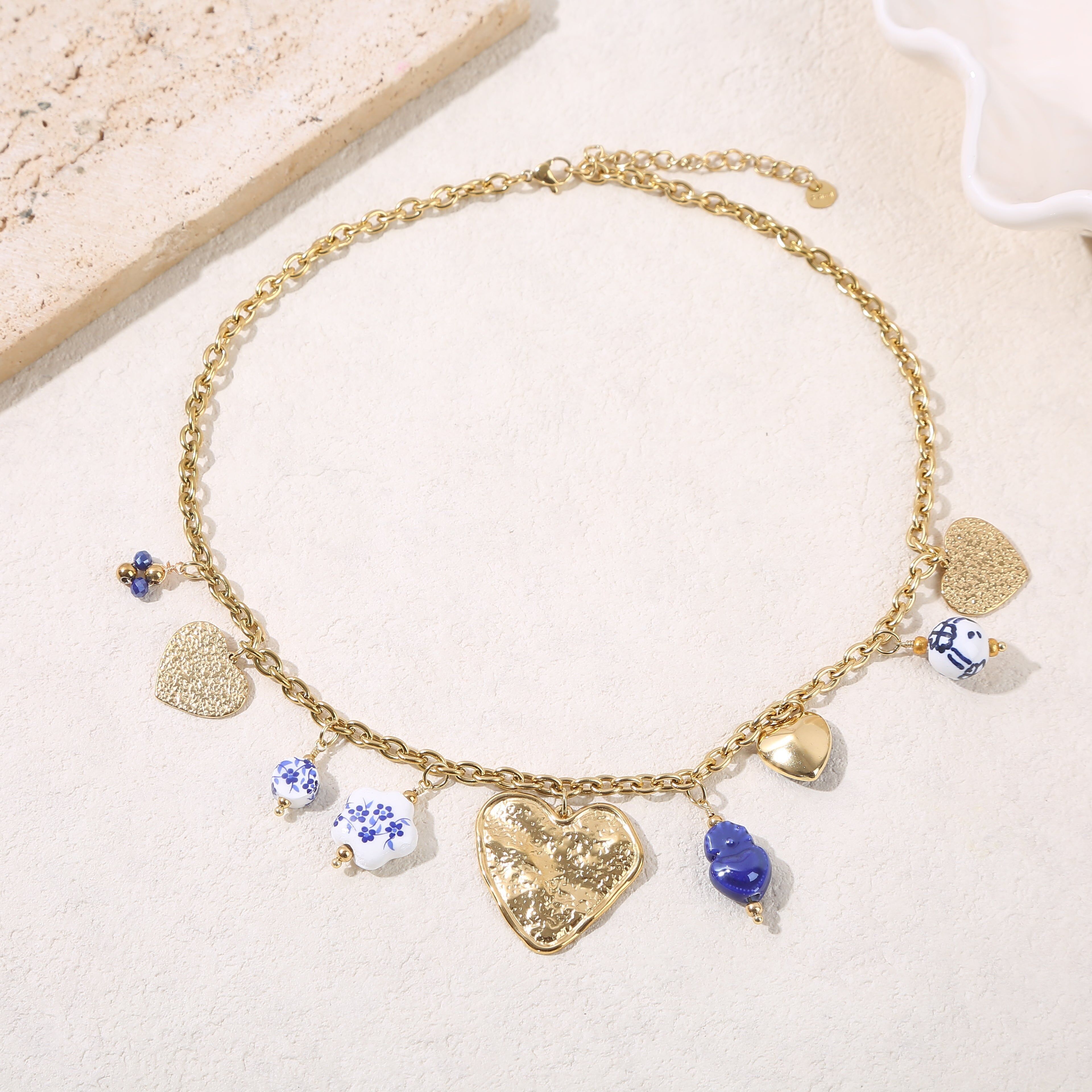 Collana a catena in oro con pendenti blu e una grande placca a forma di cuore martellato