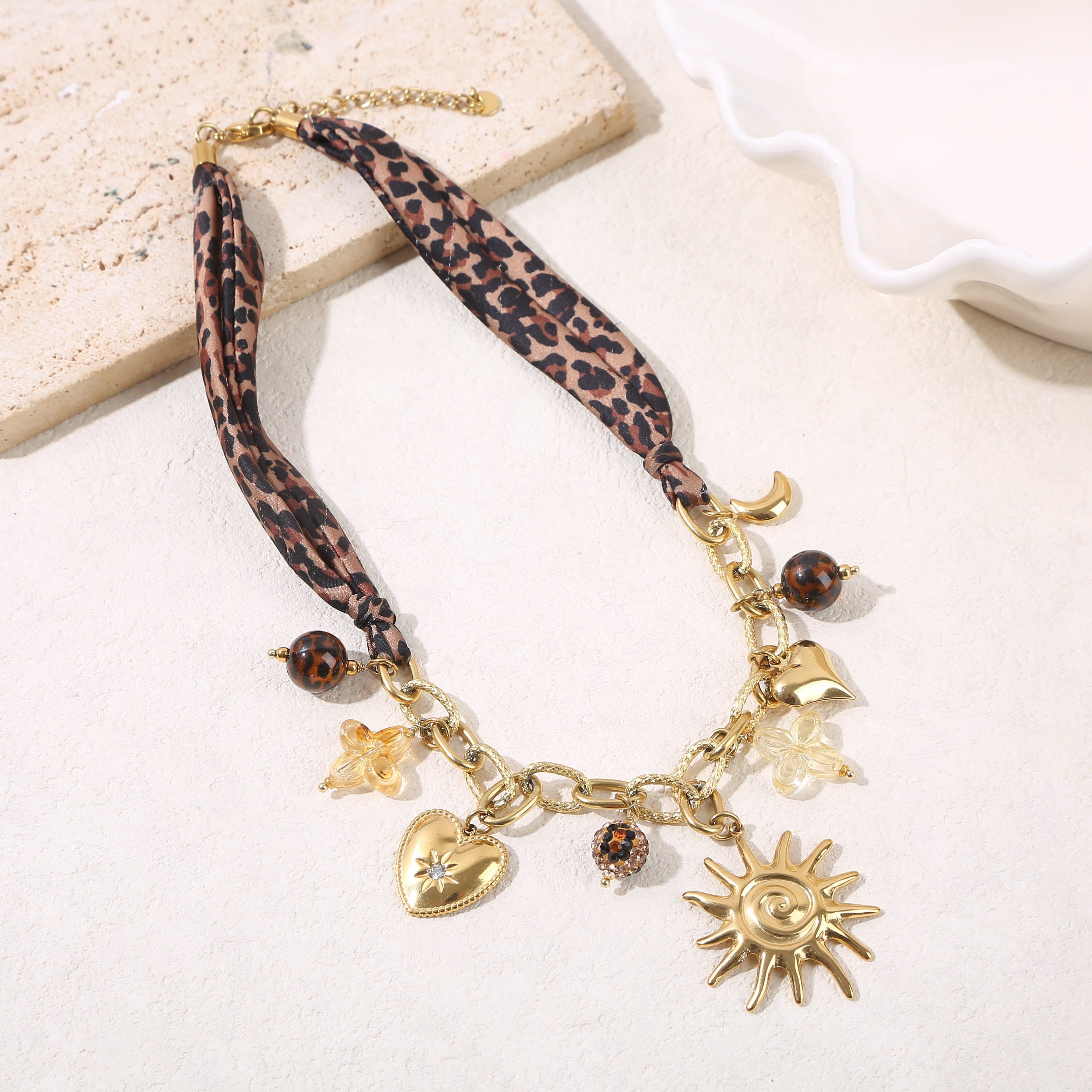 Collana con catena testurizzata in oro con tessuto leopardato, pendenti in resina e ampio sole