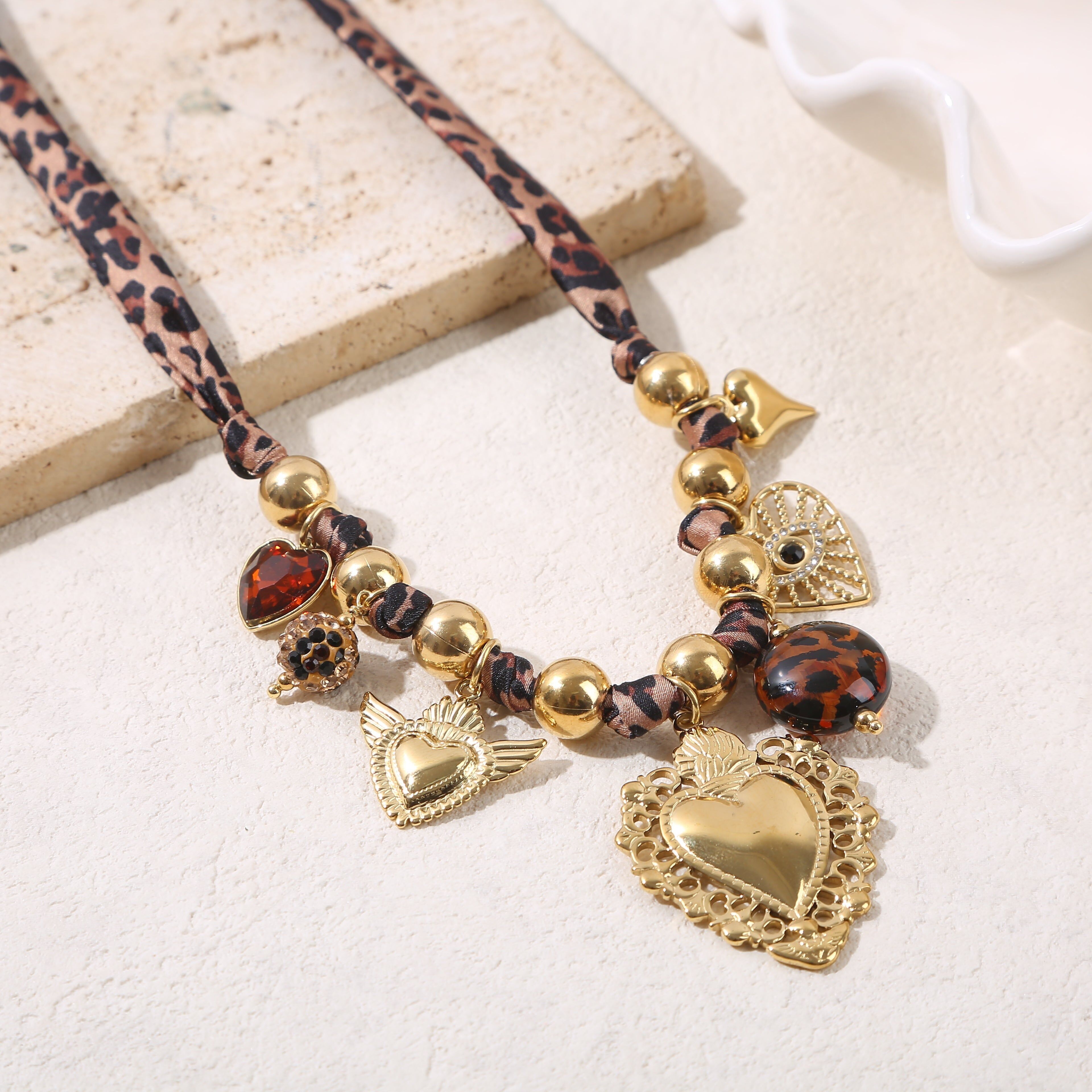 Ampia collana di perline dorate decorata con tessuto leopardato, ciondoli e un grande cuore