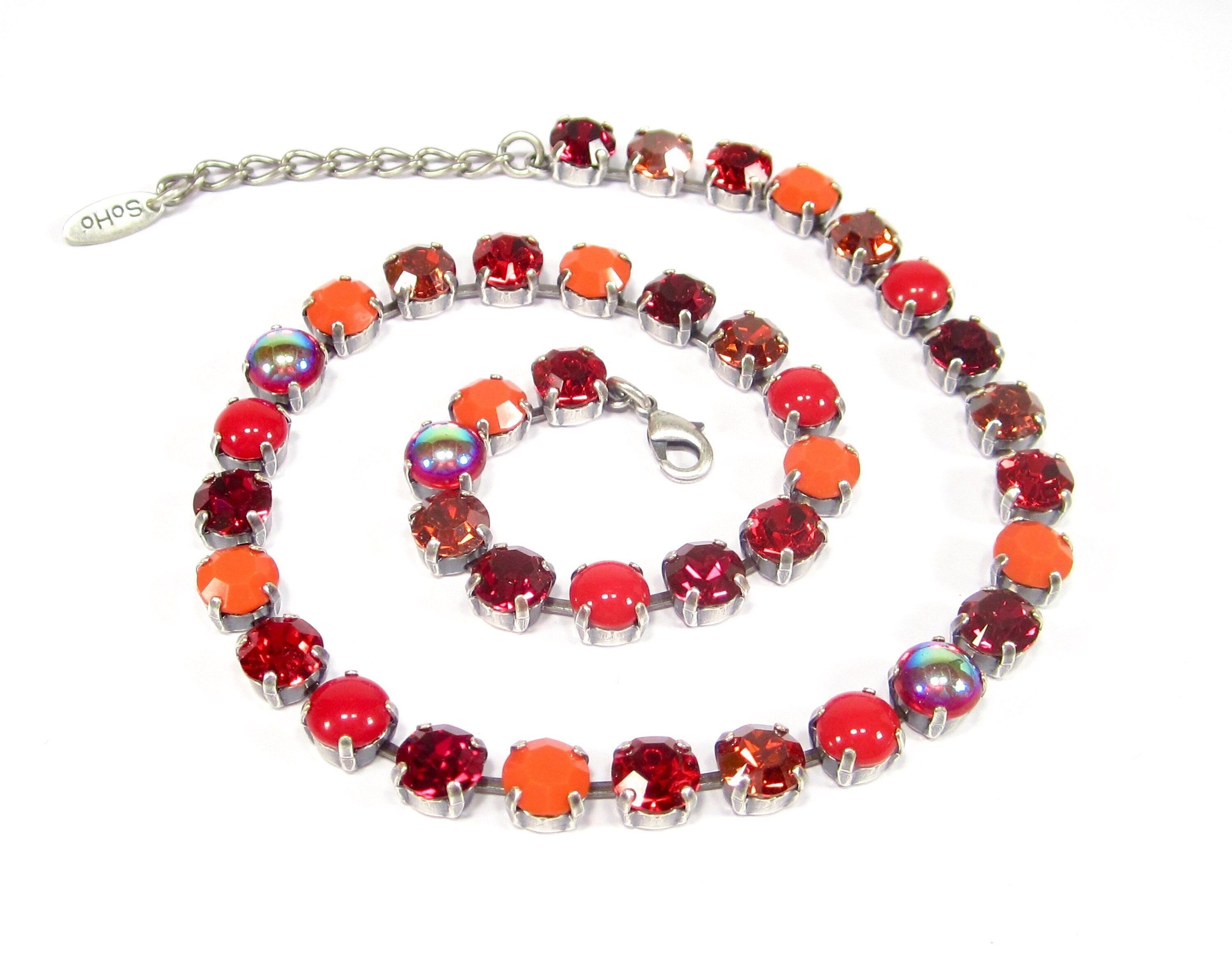 Collier rouge orné de cristaux taillés et de pierres en verre faites à la main, dans un mélange de tons rouges et orangés, fabriqué artisanalement en Allemagne.