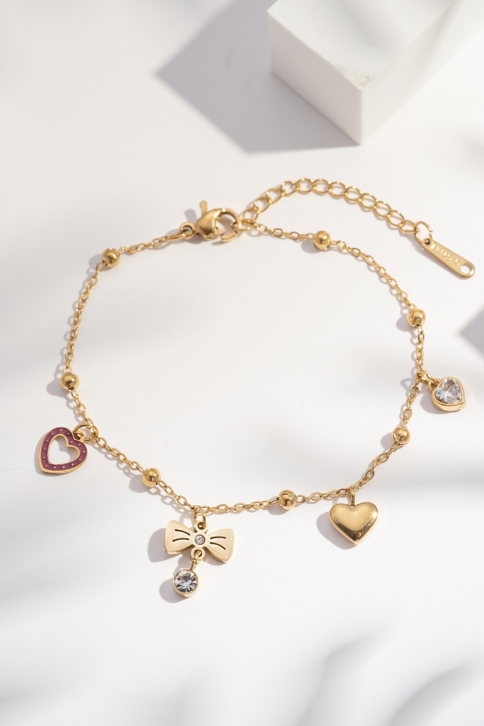 Gold-tone bracelet with heart and knot charms and steel crystals