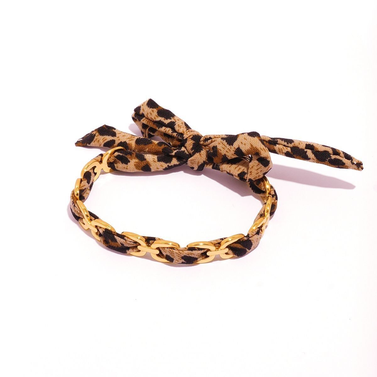 Bracciale rigido sottile regolabile color oro con motivo traforato, circondato da tessuto con stampa leopardata