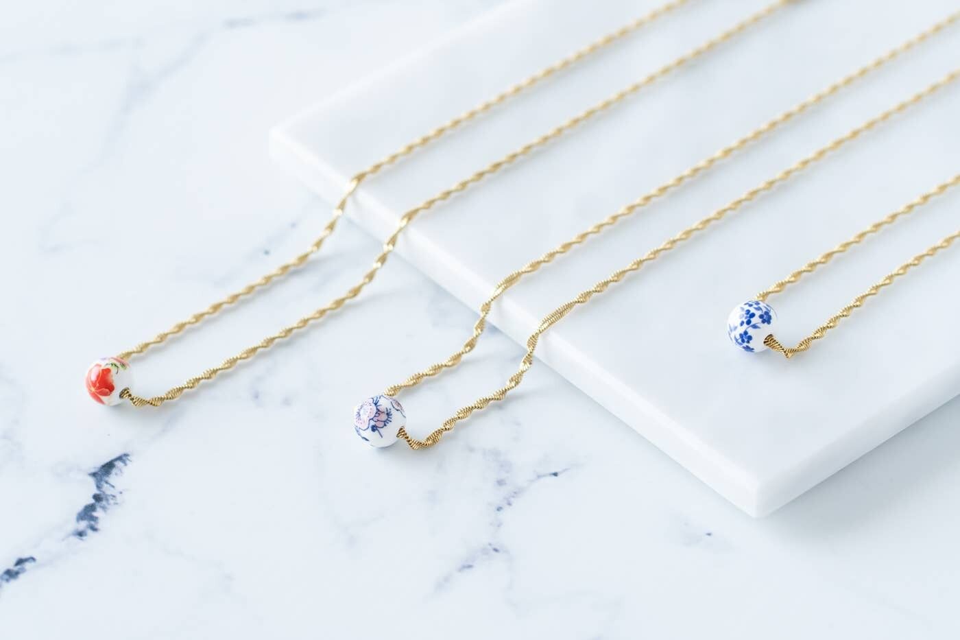 Goldene Seilkette mit floraler Keramikperle