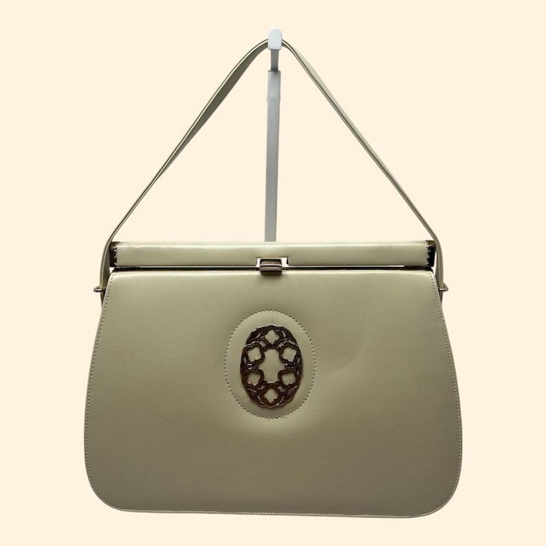 Vintage-Handtasche aus cremefarbenem Kunstleder aus den 1960er Jahren mit verziertem Metallbesatz und goldenem Verschluss – Mid-Century-Stil