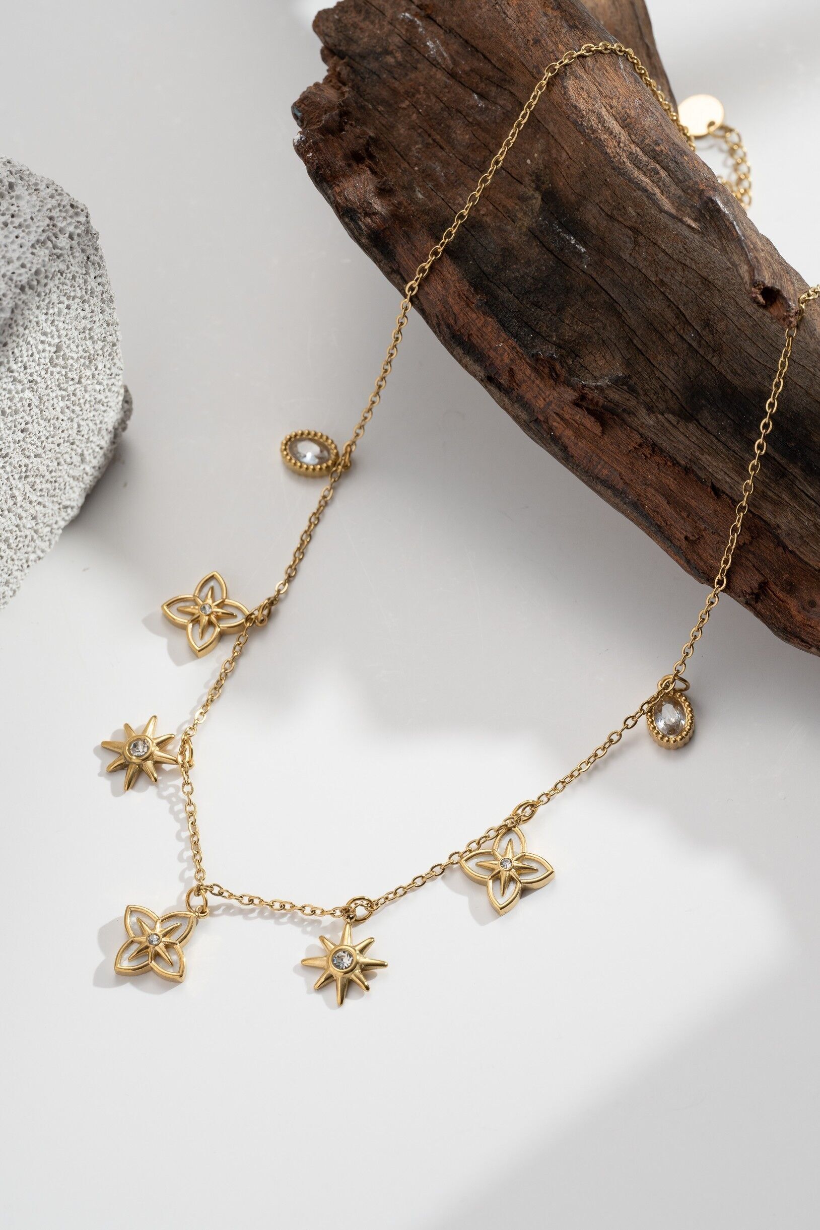 Gold necklace with stars, flowers, clear gemstones, and a celestial charm