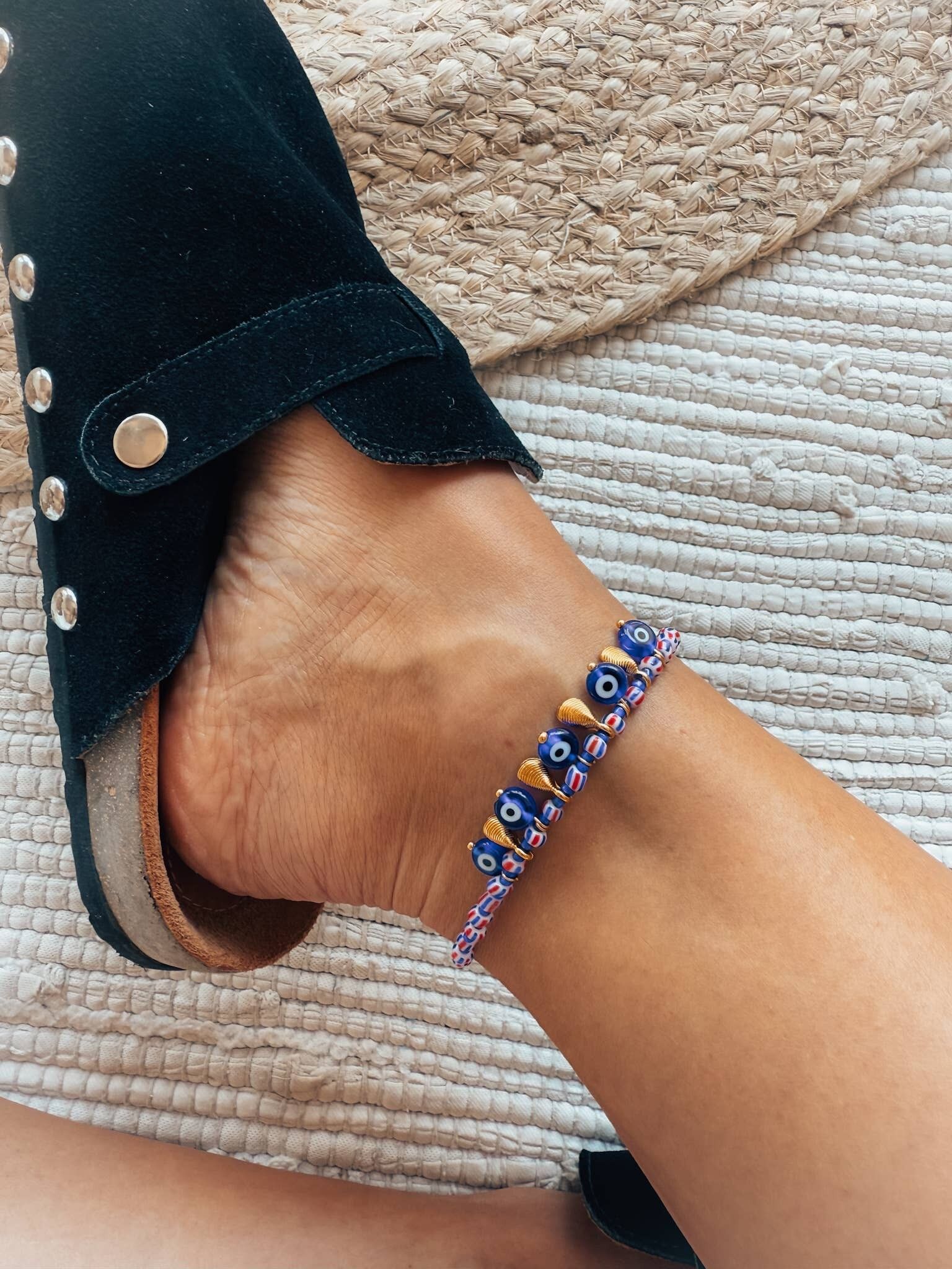 Bracelet de cheville rouge, blanc et bleu orné de perles, d'yeux et de coquillages