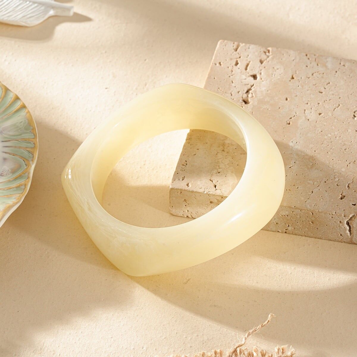 Halbdickes, weiß marmoriertes Armband aus Harz mit abgerundeter quadratischer Form.