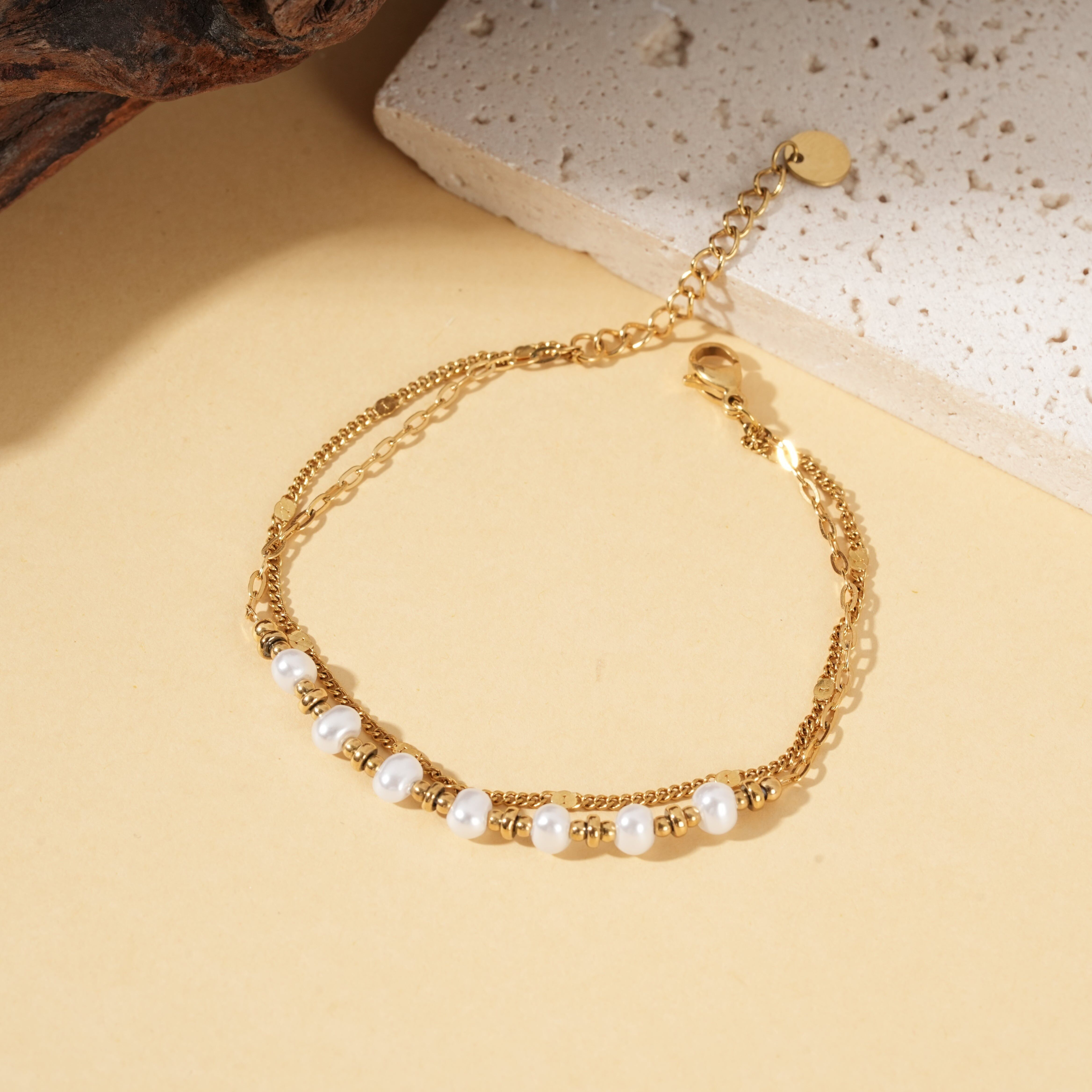 Goldenes Armband mit mehreren Ketten, verziert mit weißen Perlen