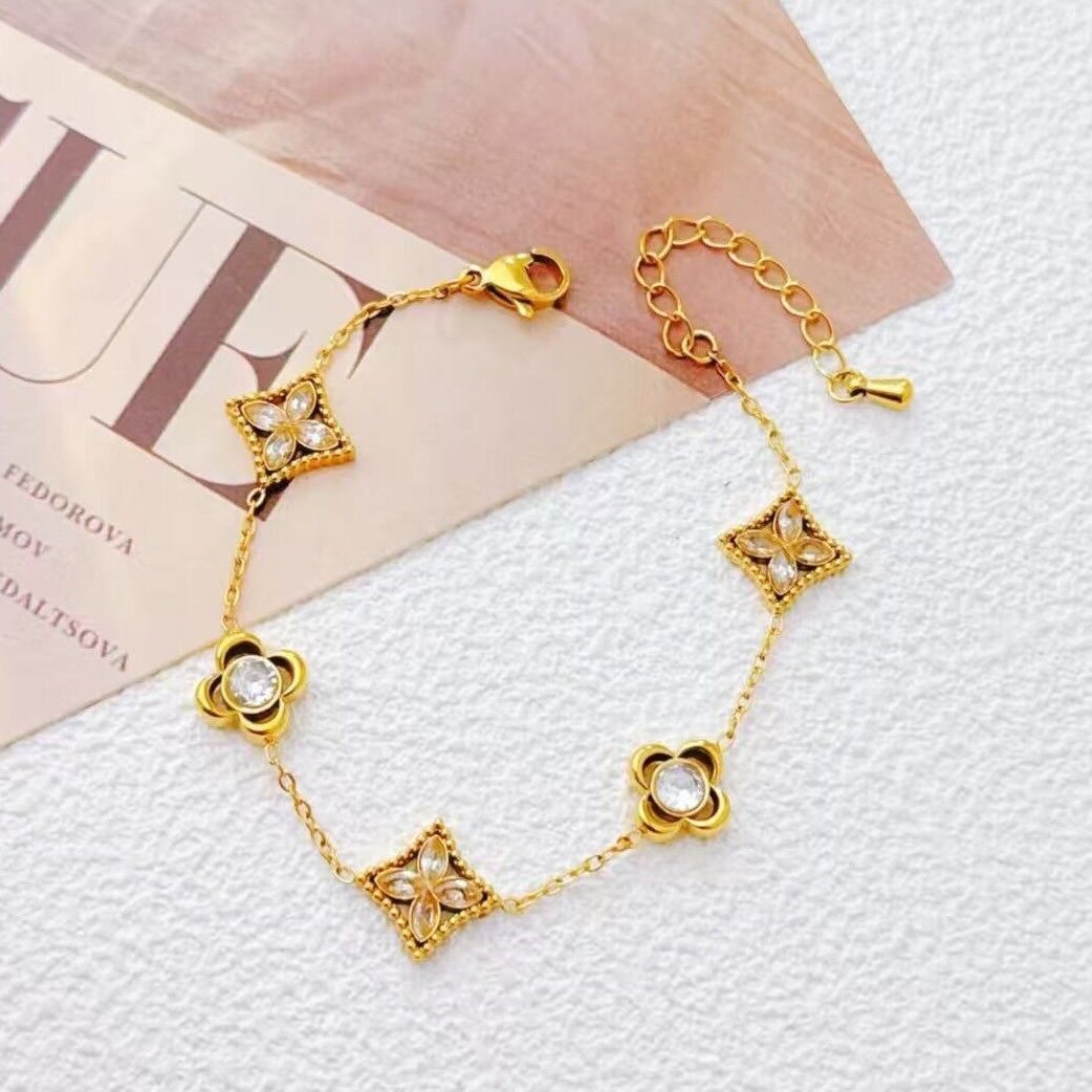 Pulsera en tono dorado con dijes luminosos de estrella y trébol.