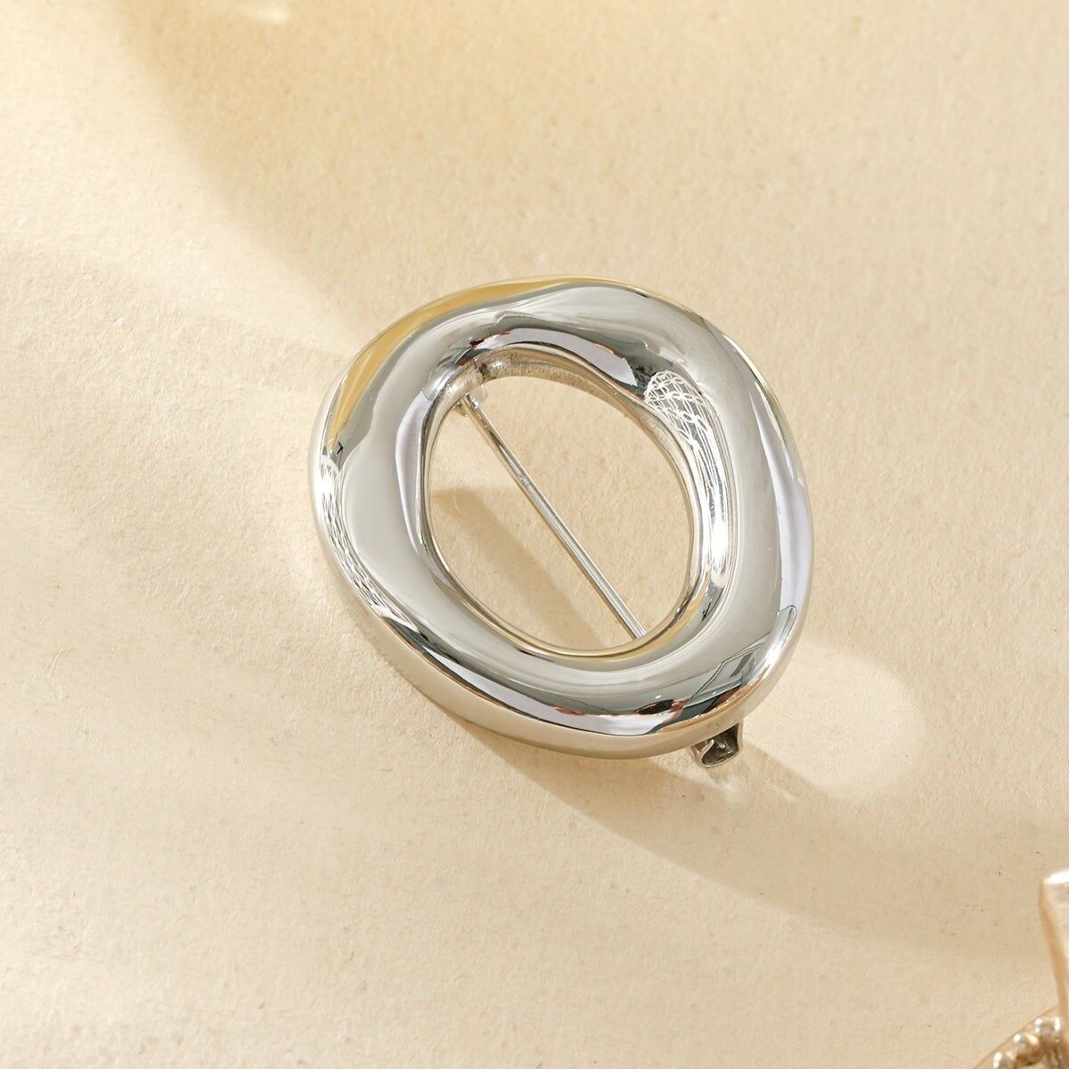 Chic and timeless oval brooch with openwork design and a glossy finish