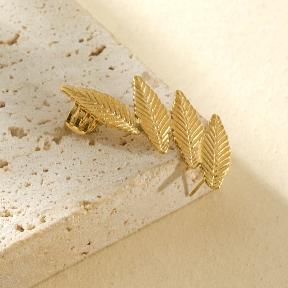 Gold earring with four ribbed leaves on the left side