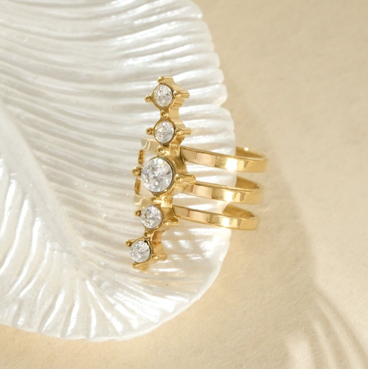 Verstellbarer, goldfarbener Ohrring mit drei übereinanderliegenden Ringen, verziert mit einer Reihe von Strasssteinen.