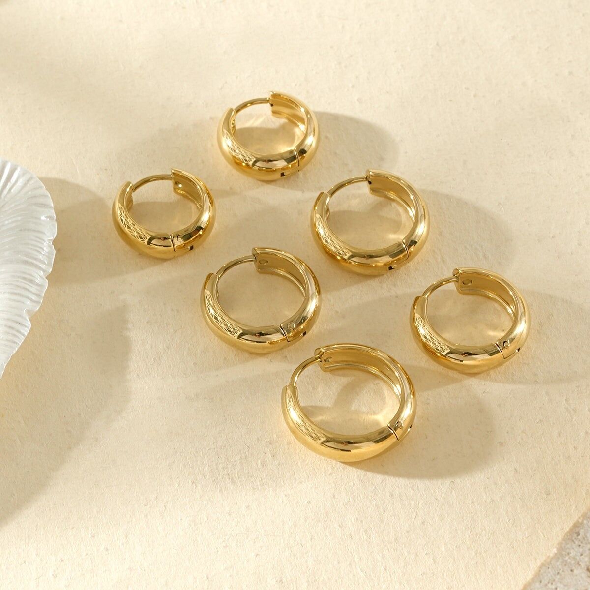 Set mit 3 Paar dicken, goldfarbenen Creolen mit glänzender Oberfläche