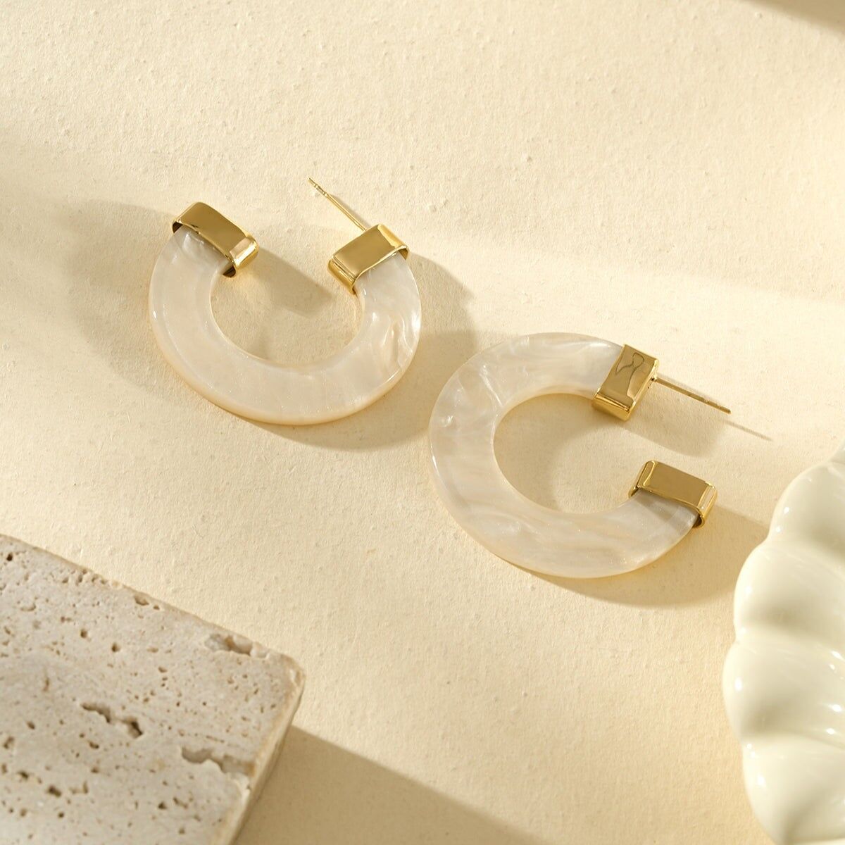 Vergoldete, perlmuttfarbene Halbcreolen aus Harz