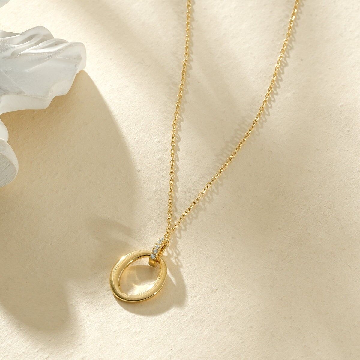 Eine zarte Goldkette, verziert mit Ovalen in verschiedenen Größen und einem Strass-Oval.