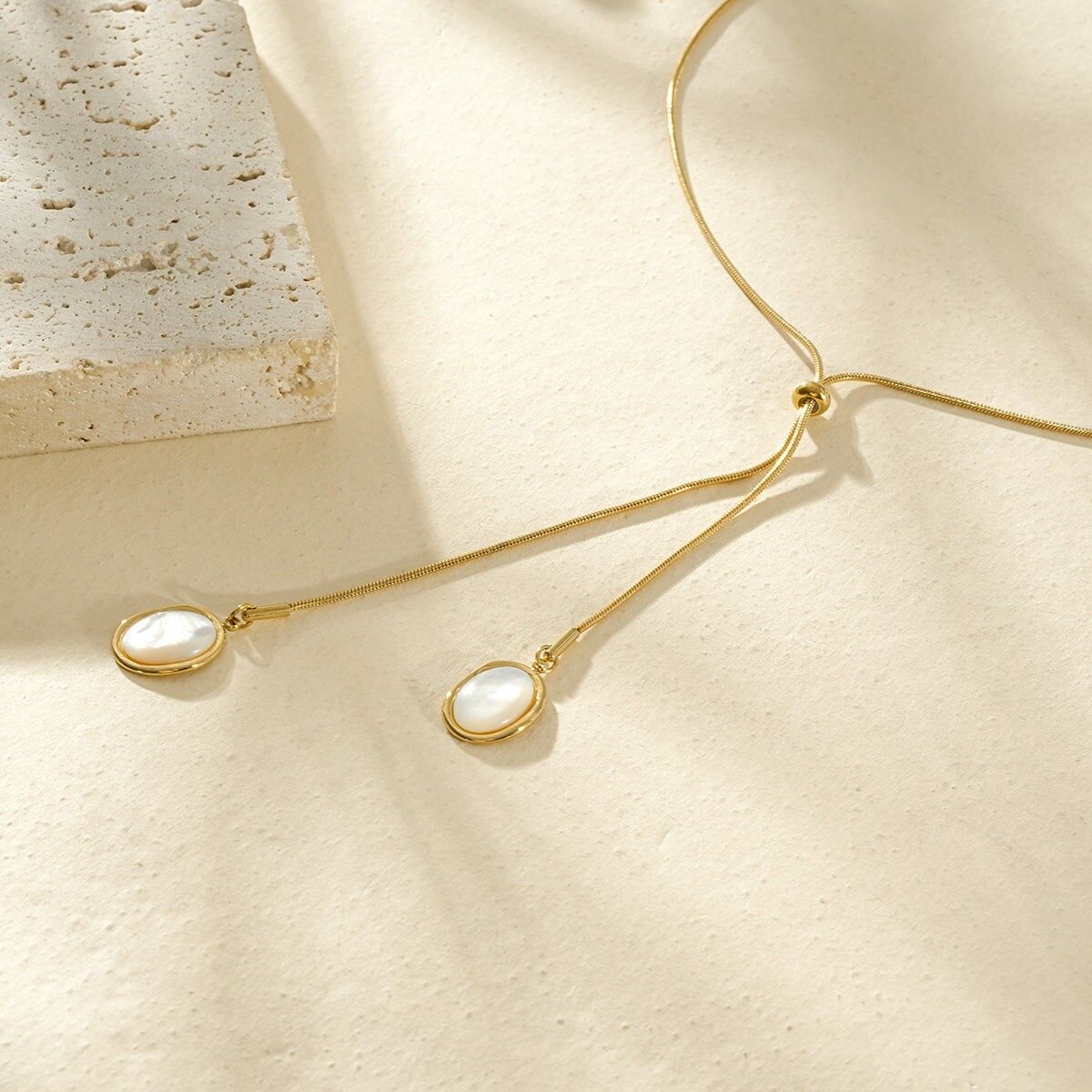 Goldfarbene Schiebekette mit zwei ovalen Anhängern aus Kunstharz in Perlmuttoptik