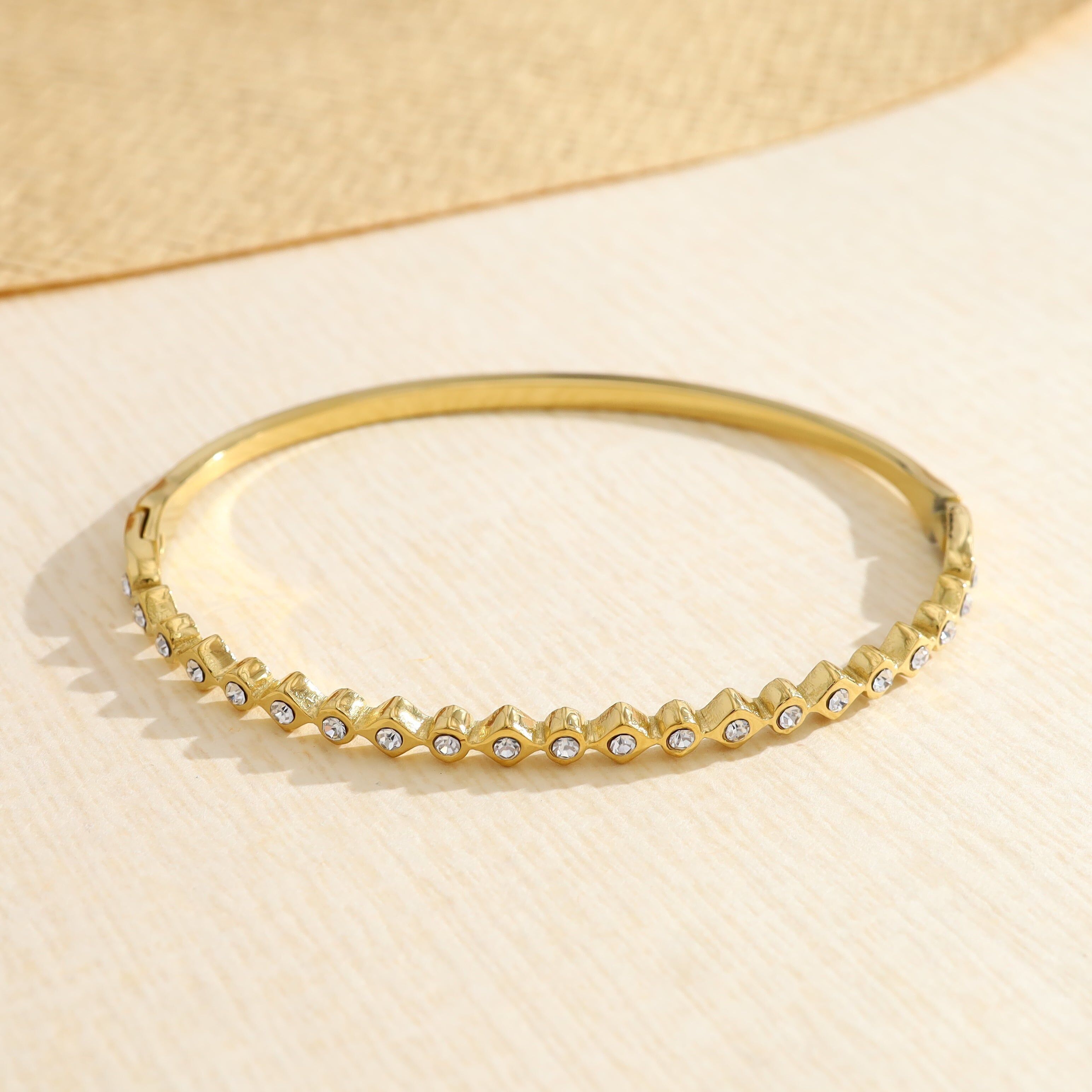 Goldener Armreif, verziert mit runden und rautenförmigen Strasssteinen