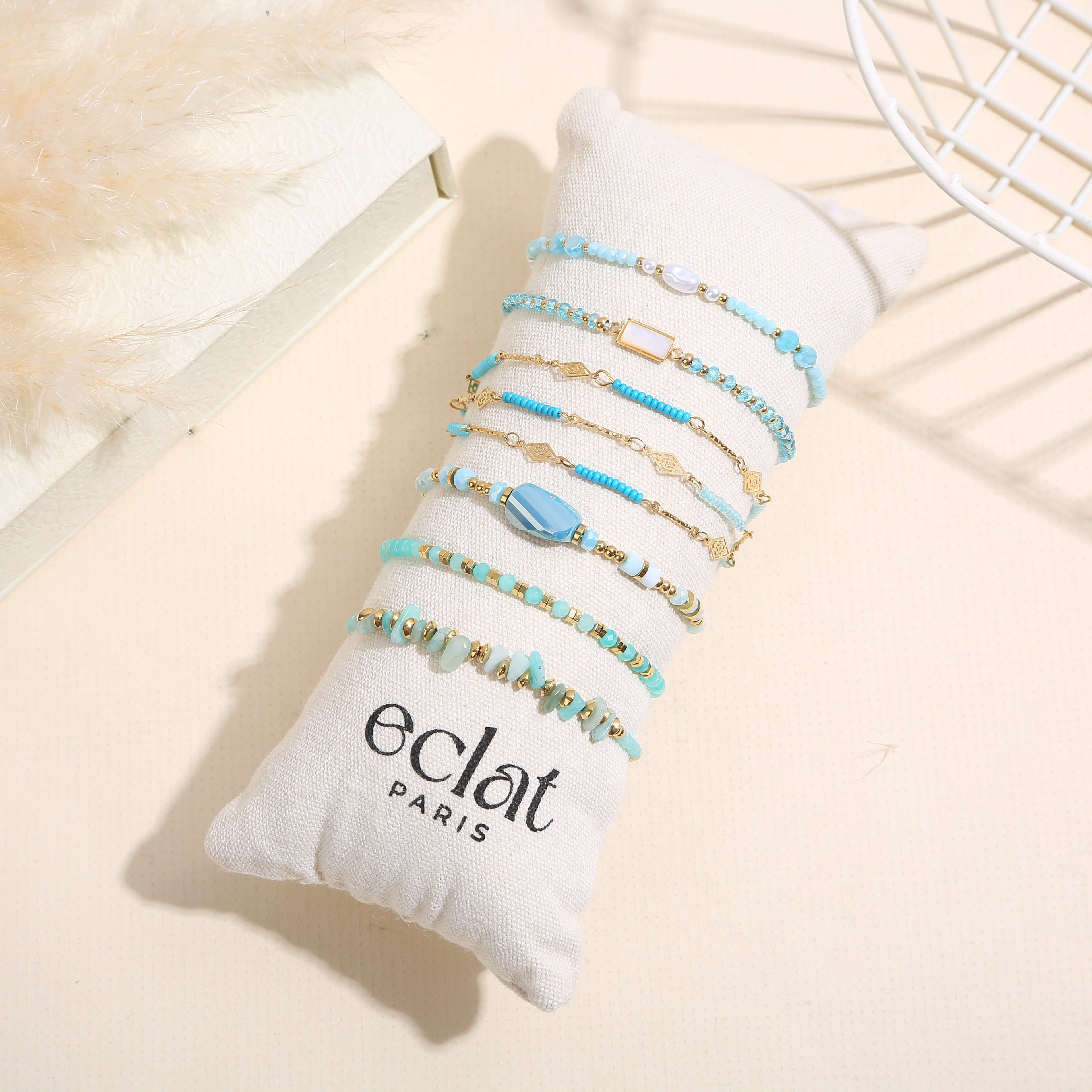 Set aus 8 goldenen Armbändern in Blautönen auf einem Kissen