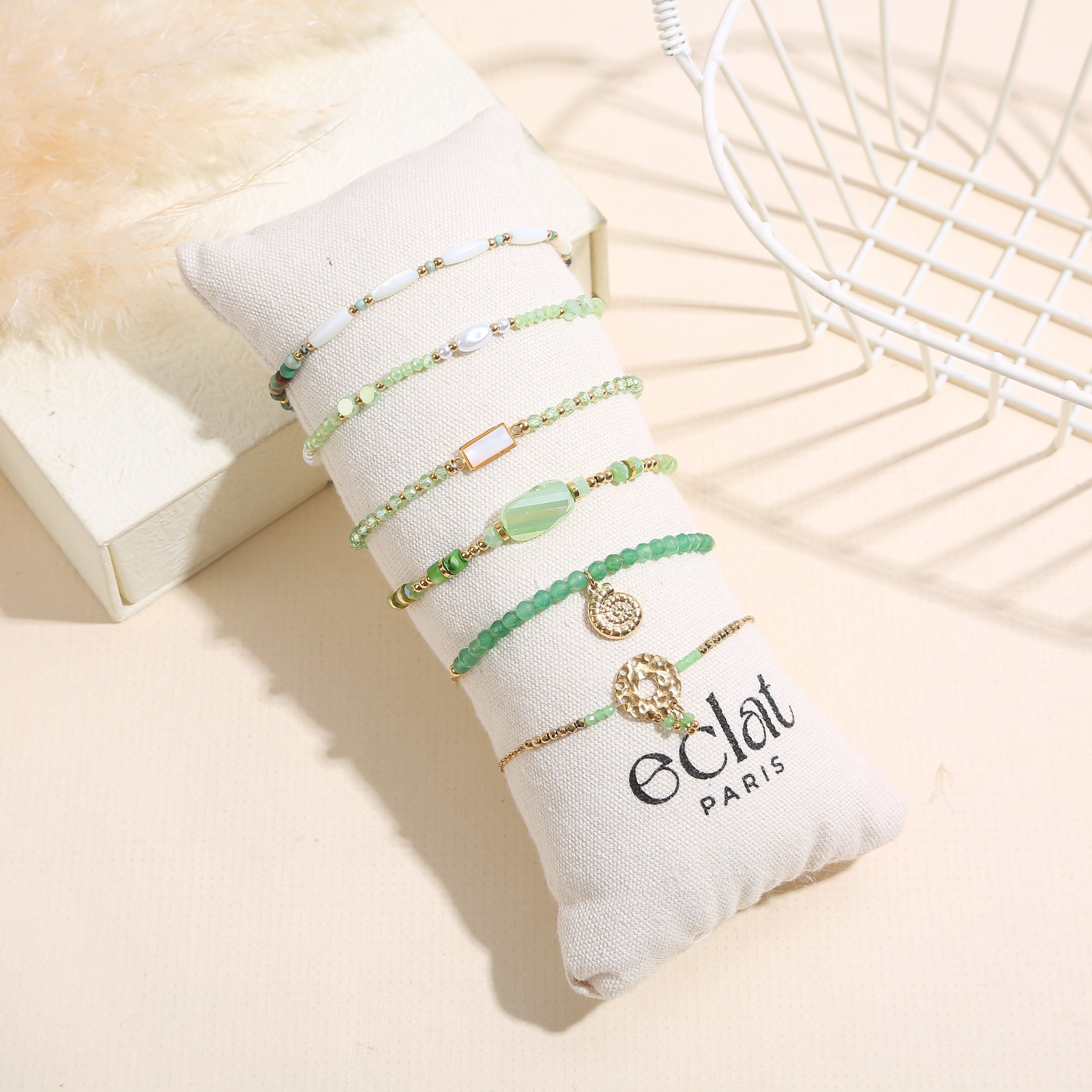 Set aus 6 goldenen Armbändern in Grüntönen auf einem Kissen