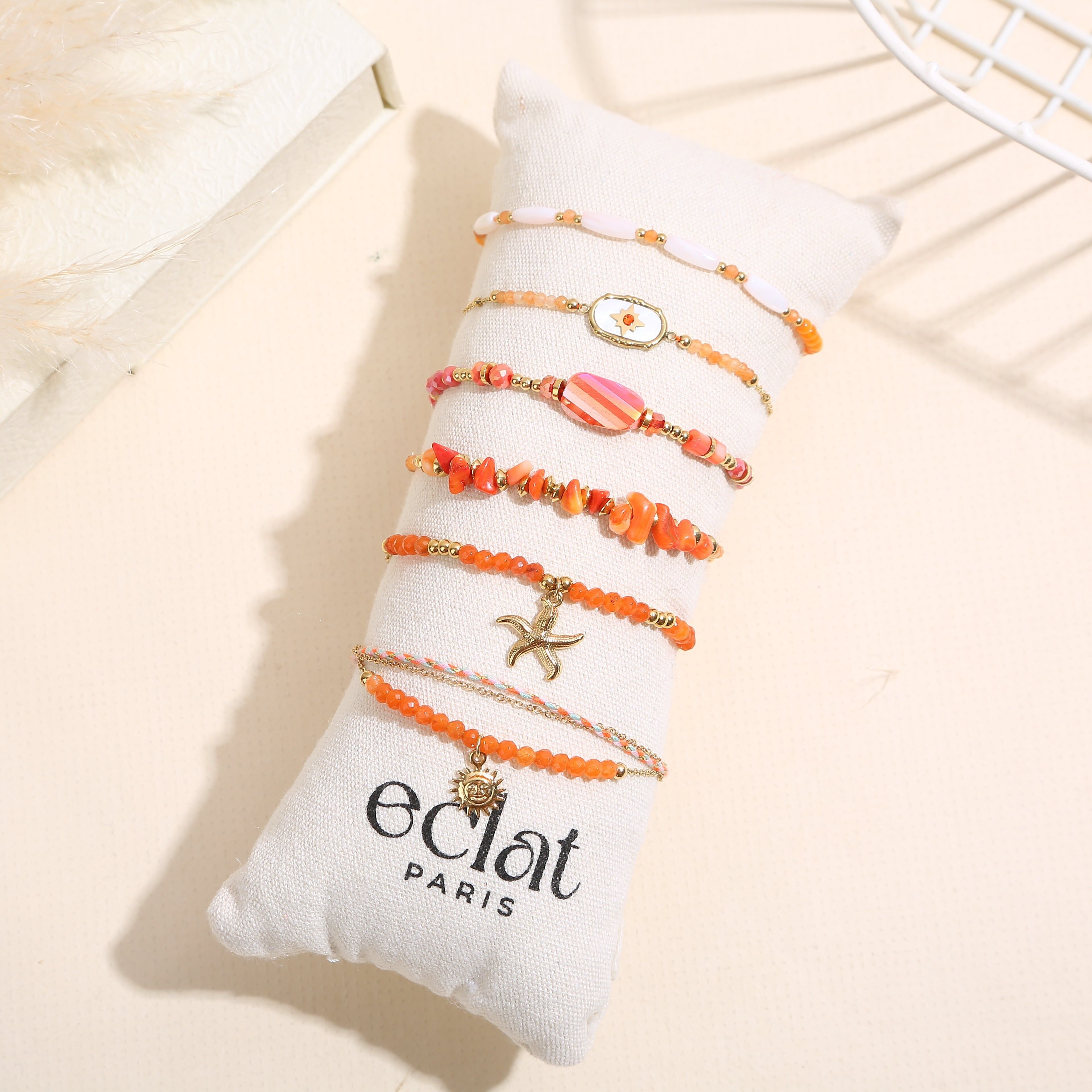 Set aus 6 goldfarbenen Armbändern in Orangetönen auf einem Kissen