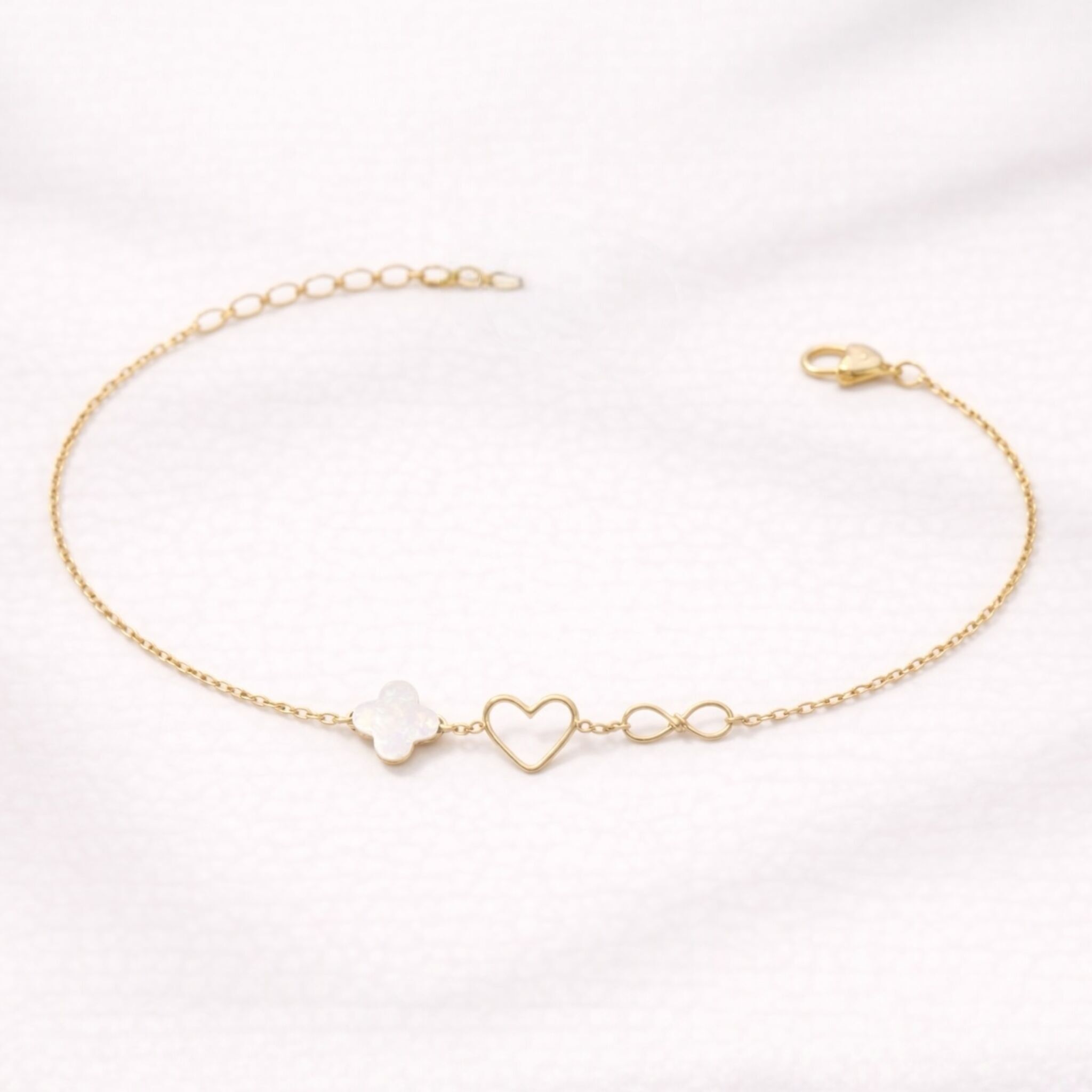 Asymmetrical bracelet with heart, infinity symbol & mother-of-pearl clover – gold-plated stainless steel & gold-filled