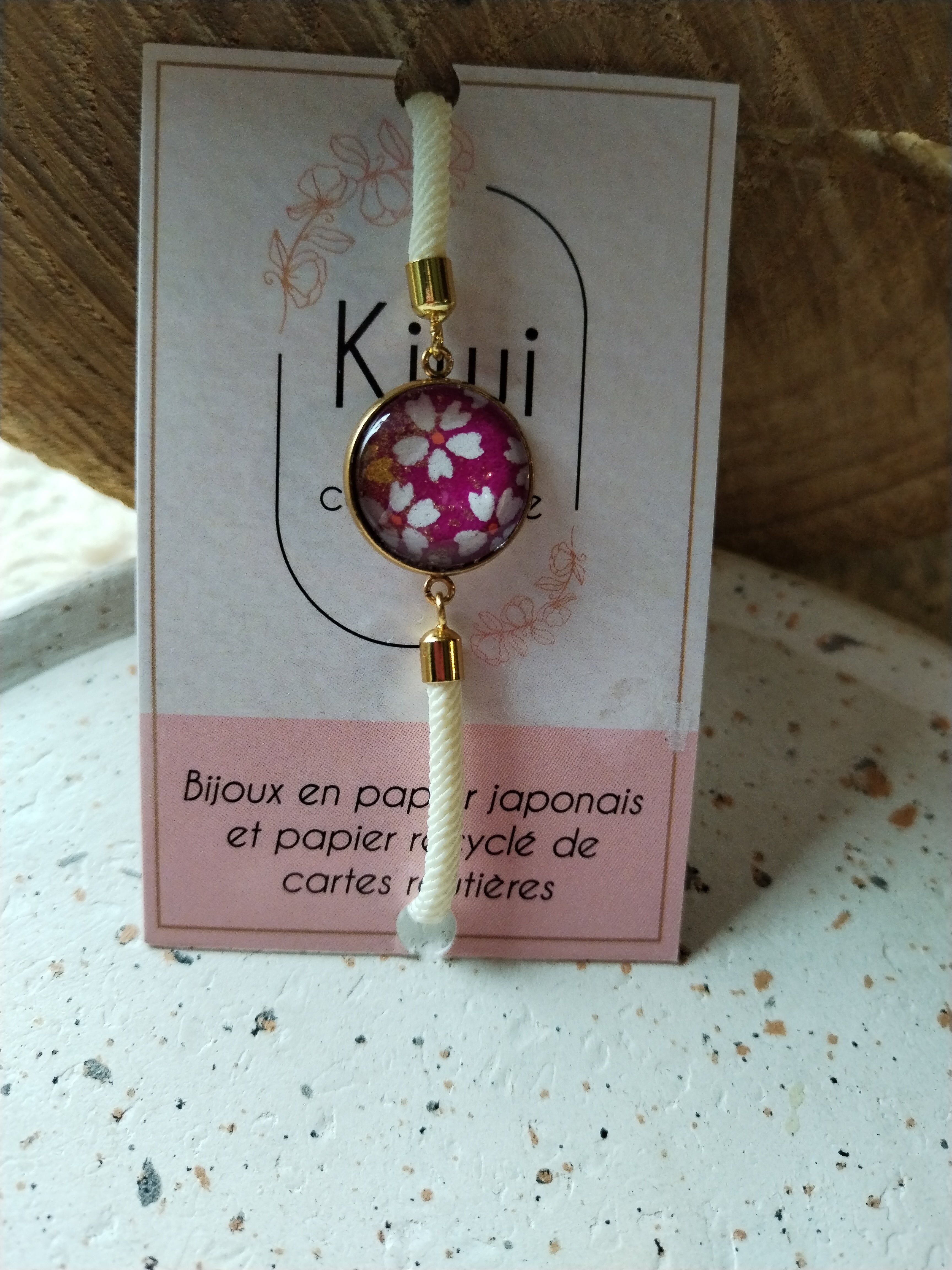 Adjustable beige cotton bracelet with a pink cabochon and white flower.