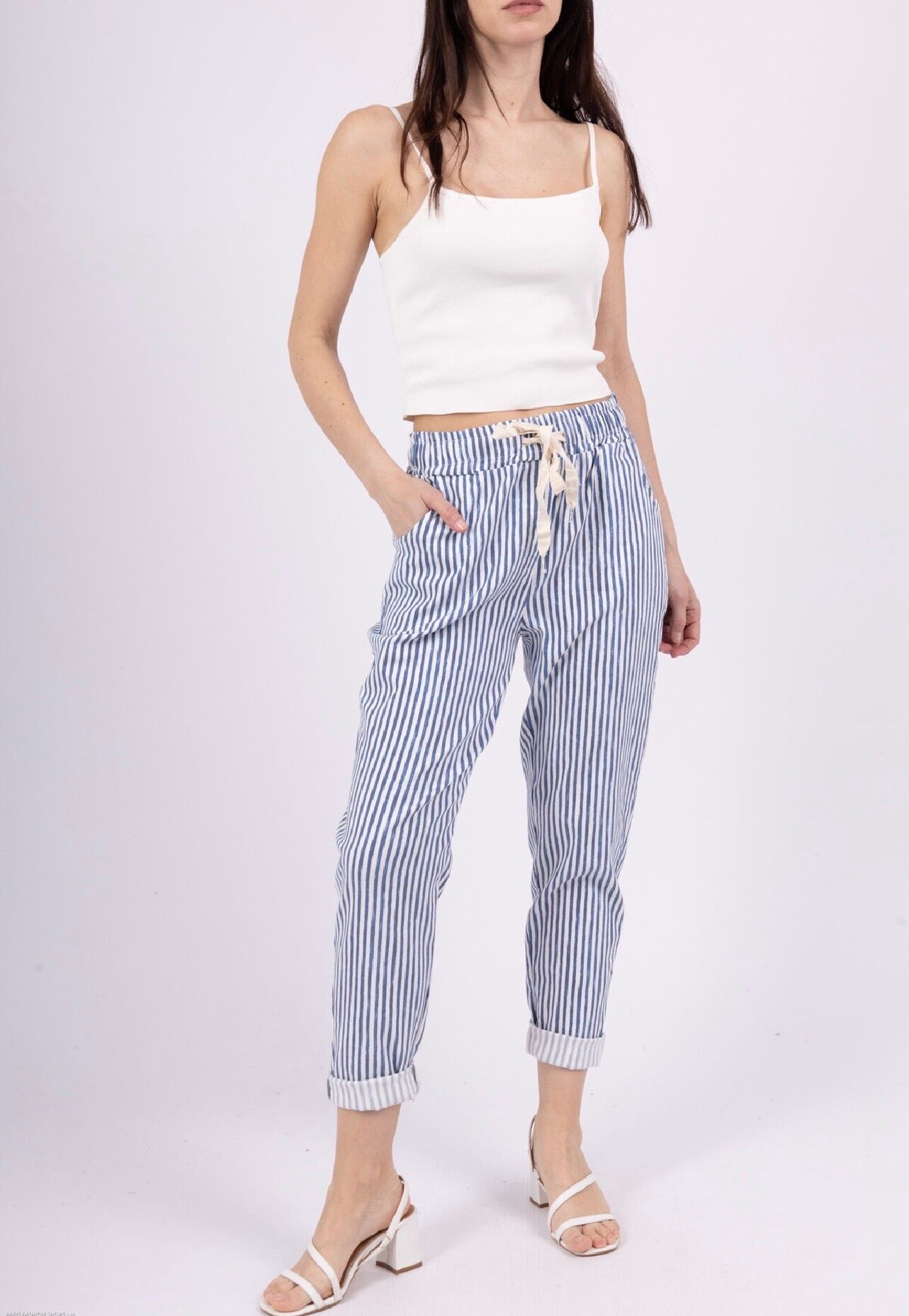 Summer trousers with stripes on a white background, featuring side pockets and an adjustable waist thanks to an ecru drawstring.