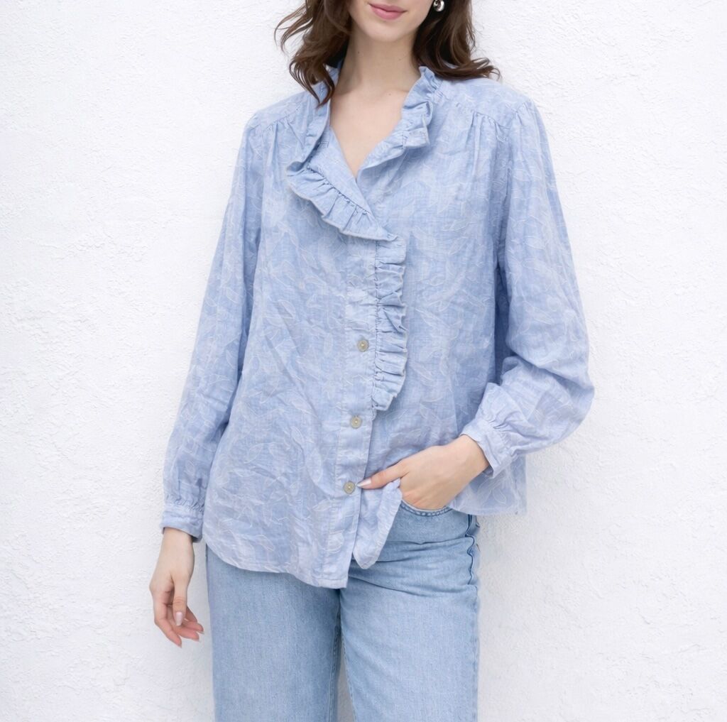 Long-sleeved shirt with buttoned cuffs and a V-neck, enhanced by a ruffled flounce that extends onto the front with floral embroidery.