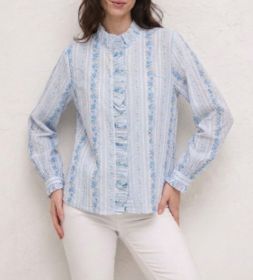 Bohemian shirt with long sleeves, buttoned and ruffled cuffs, a gathered stand-up collar, and a ruffle that matches the ruffle along the entire length of the button placket. Features a floral pattern with thin vertical stripes.