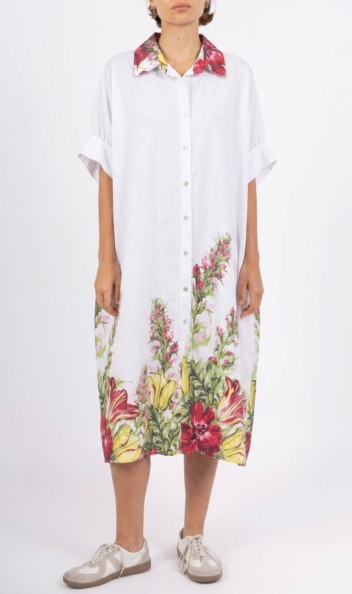 A loose-fitting, bohemian midi shirt dress with short, wide sleeves and dropped shoulders, accentuated by a colorful floral frieze detail at the hem that adorns the entire bottom of the dress and is echoed on the collar.
