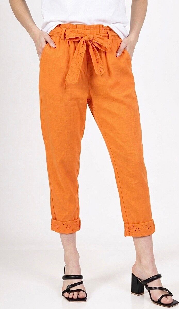 High-waisted, cropped carrot-cut trousers in cotton linen with two side pockets, a tie belt, and eyelet embroidery at the leg openings.