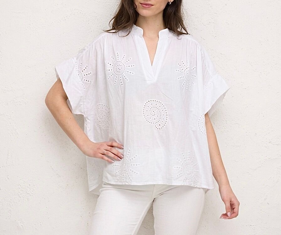Loose-fitting bohemian blouse with short sleeves, mandarin collar, and eyelet embroidery with a sun and seashell motif on the front.