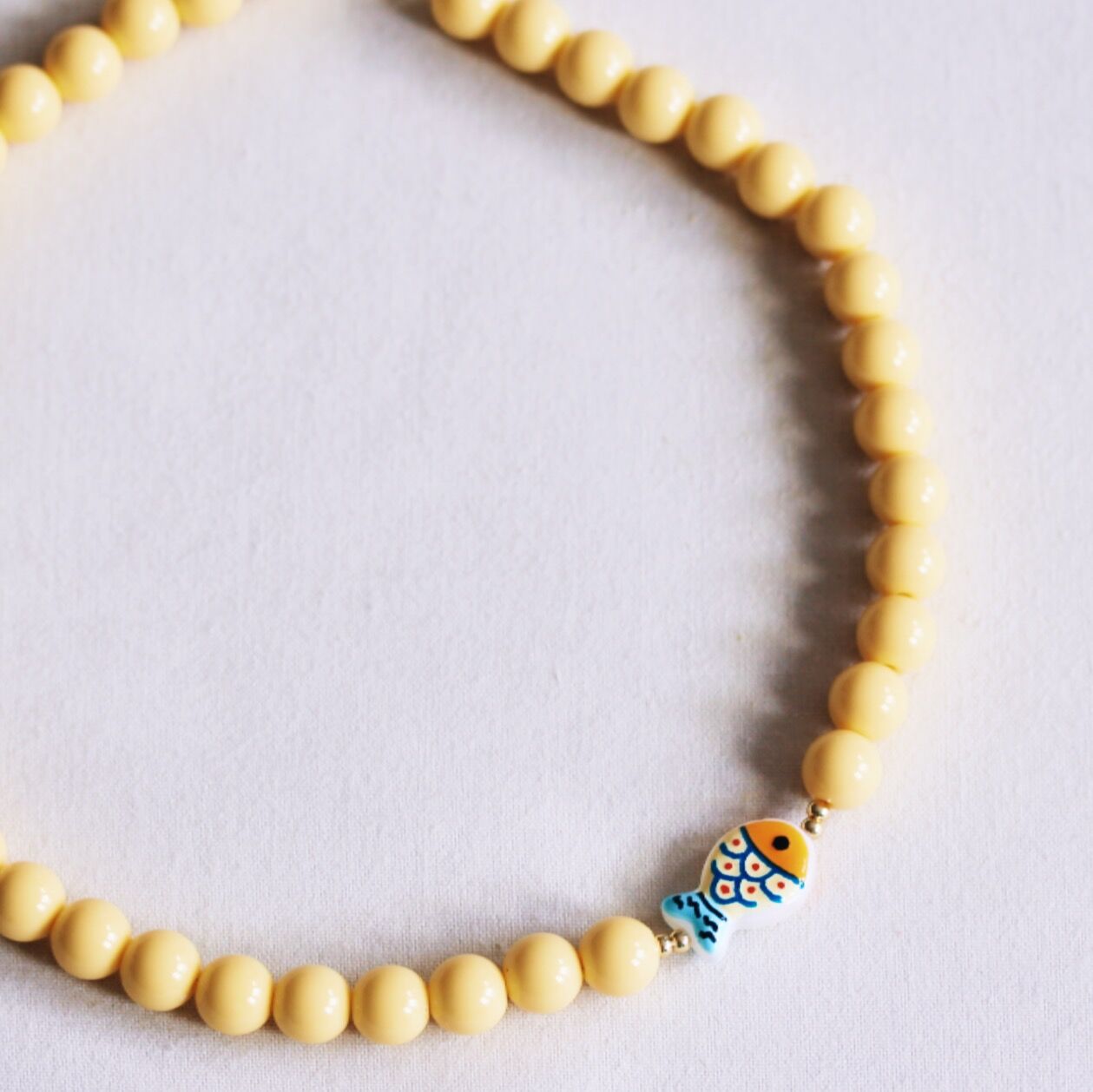 Perlenkette mit Fischmotiv – gelb
