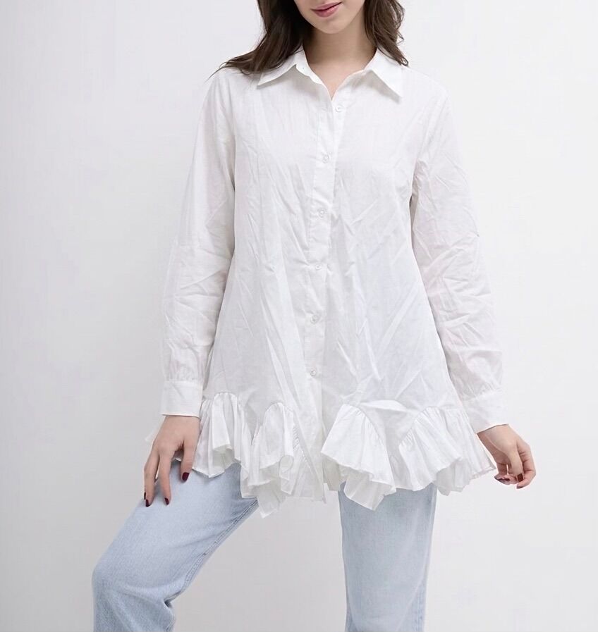 Flared tunic-shirt with long sleeves, buttoned cuffs, shirt collar, and an asymmetrical finish with wide gathered ruffles at the bottom.